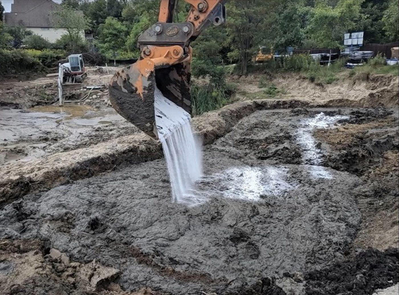 Excavator pouring Ultrabind into wet slurry to bind solids