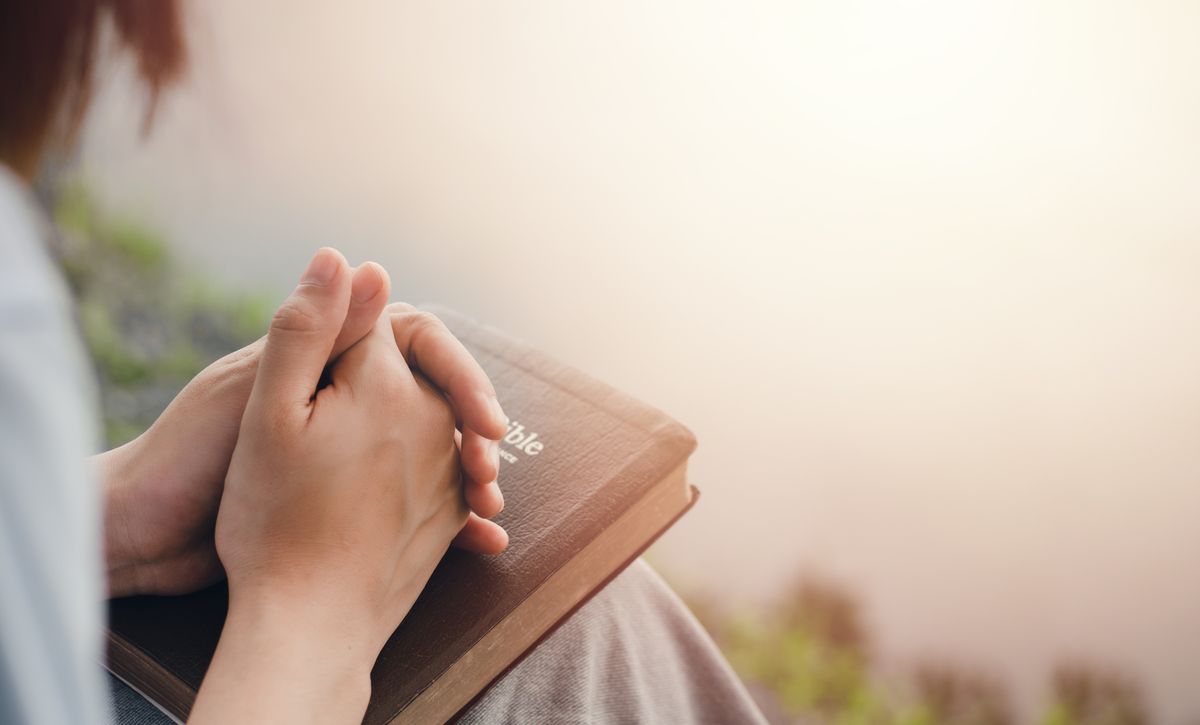 Hands resting on a Bible in prayer