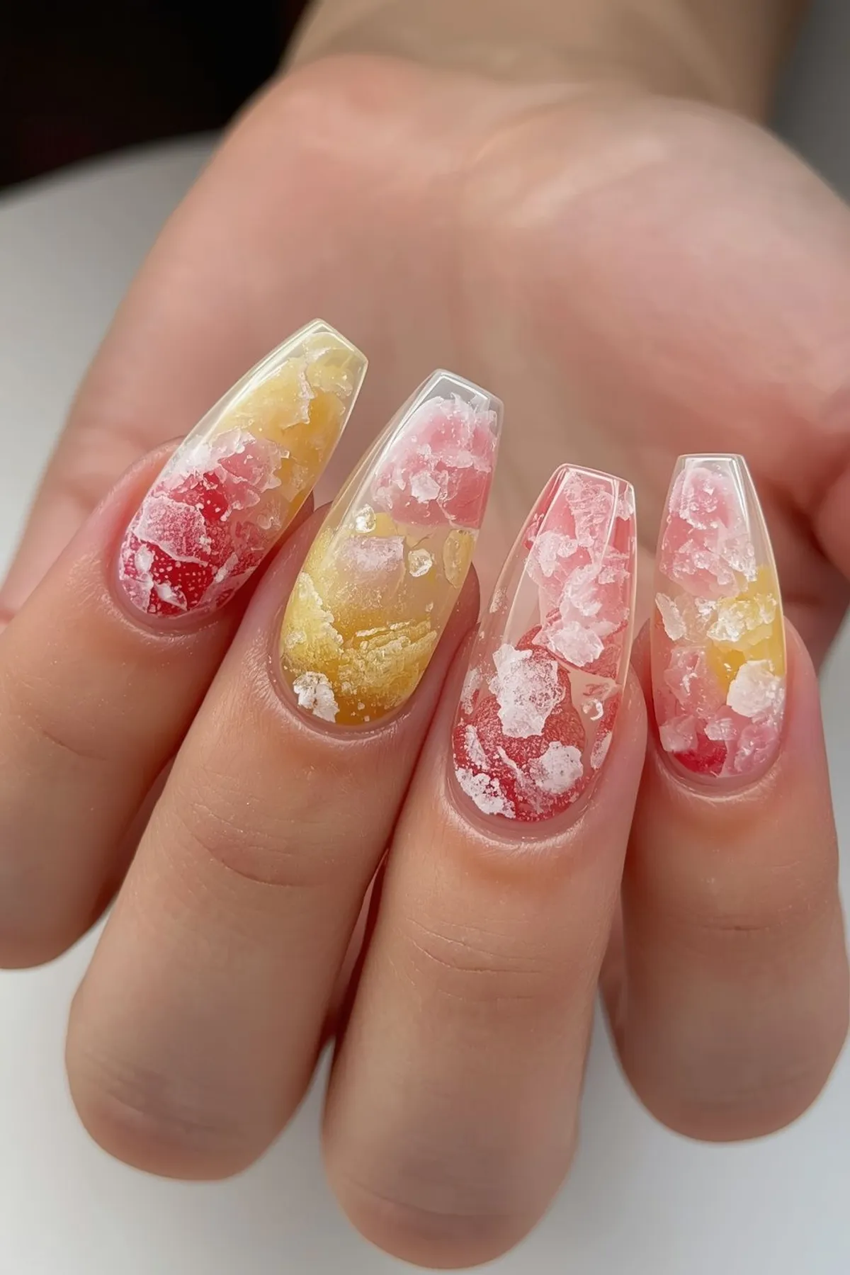 Textured summer nails with pink and yellow crushed ice effect, translucent gel nails with 3D icy design on long almond shape