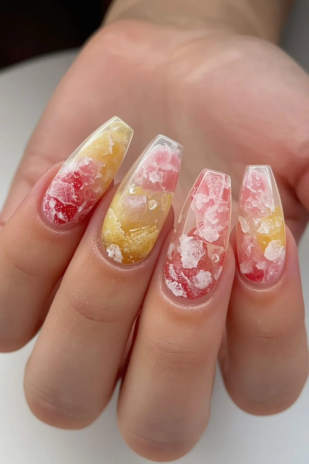 Textured summer nails with pink and yellow crushed ice effect, translucent gel nails with 3D icy design on long almond shape