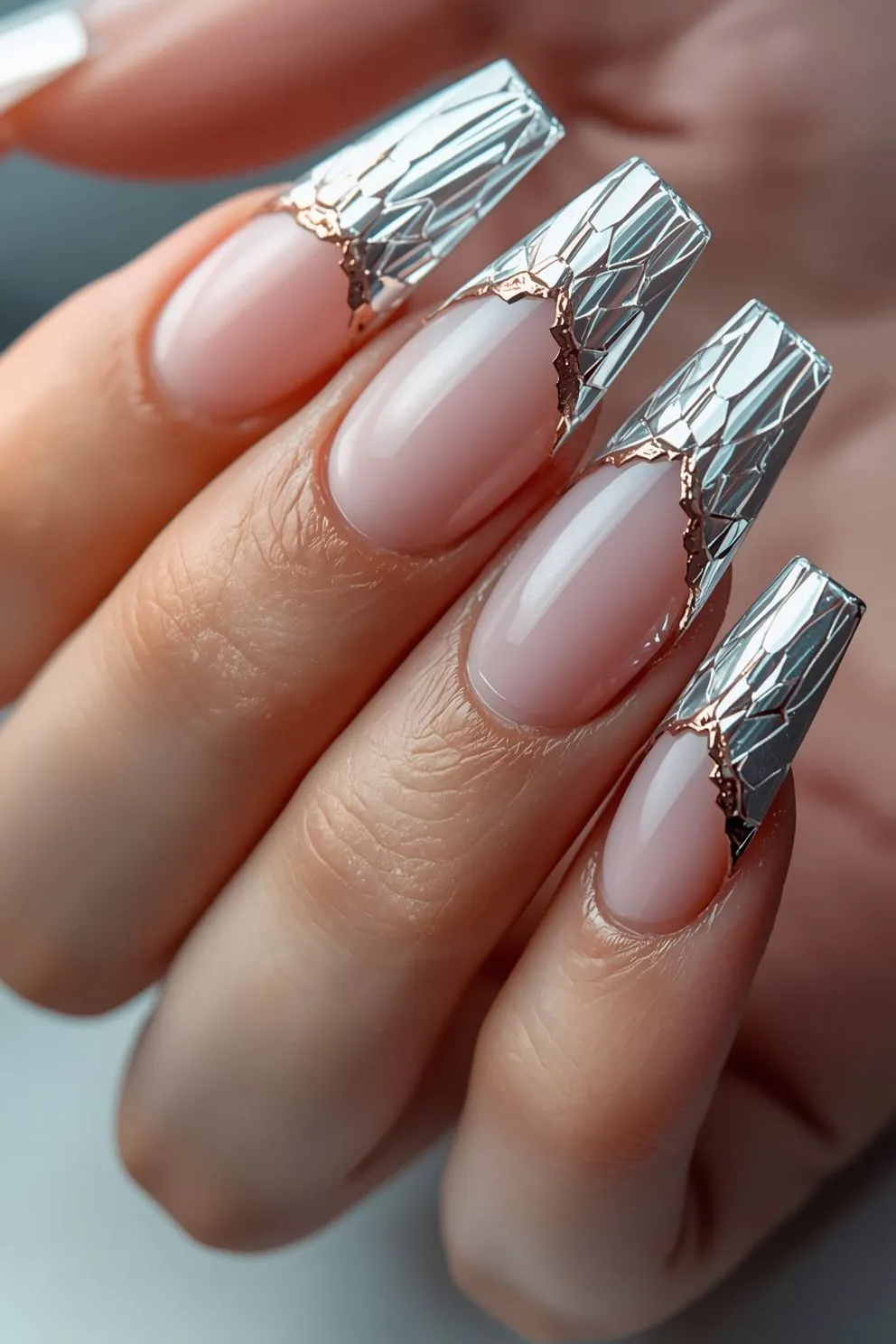 Modern French tip nails with reflective silver chrome tips and cracked crystal design on nude base, long coffin-shaped nails