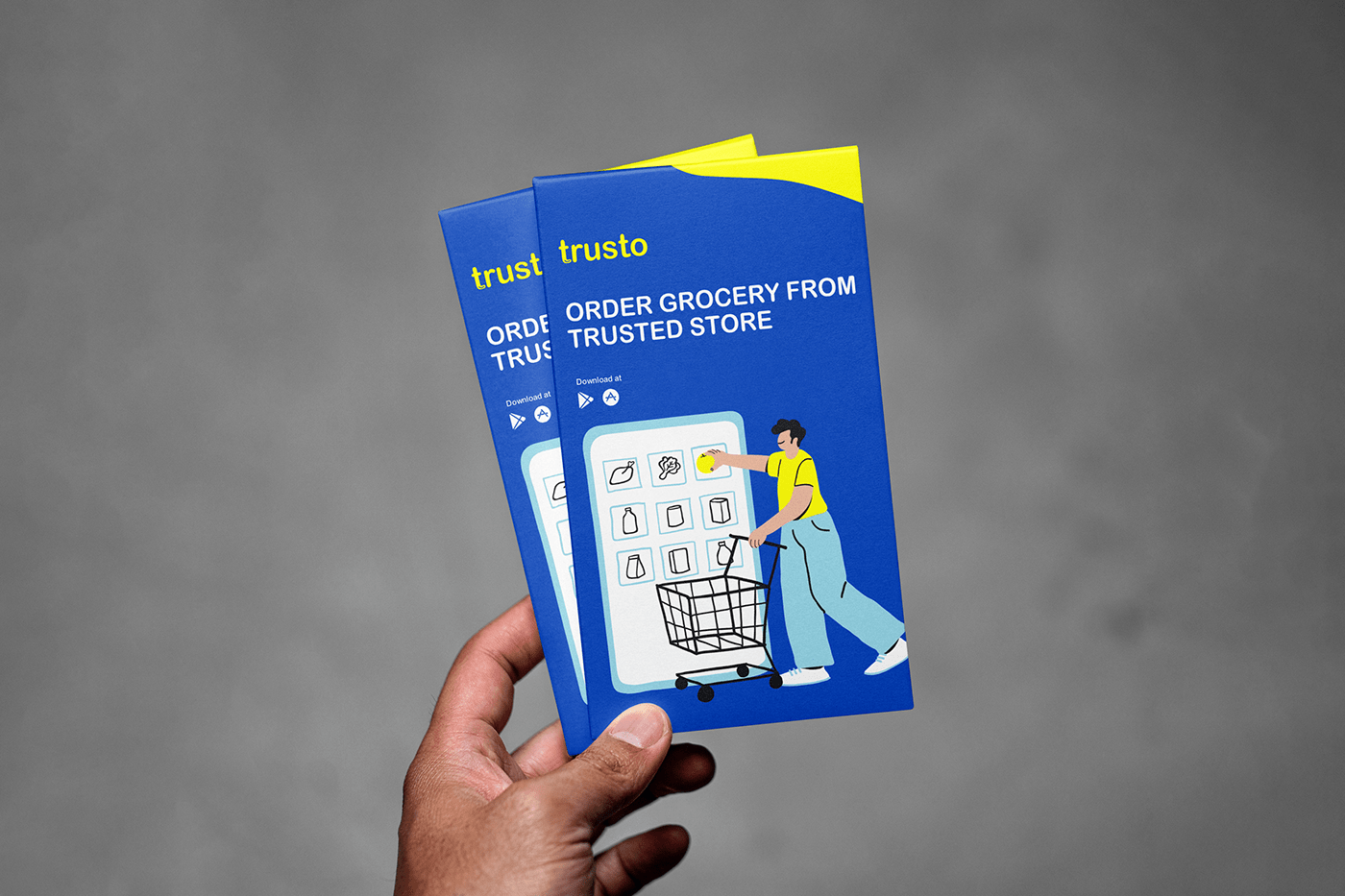Hand holding two blue and yellow Trusto flyers with the line Order grocery from trusted store