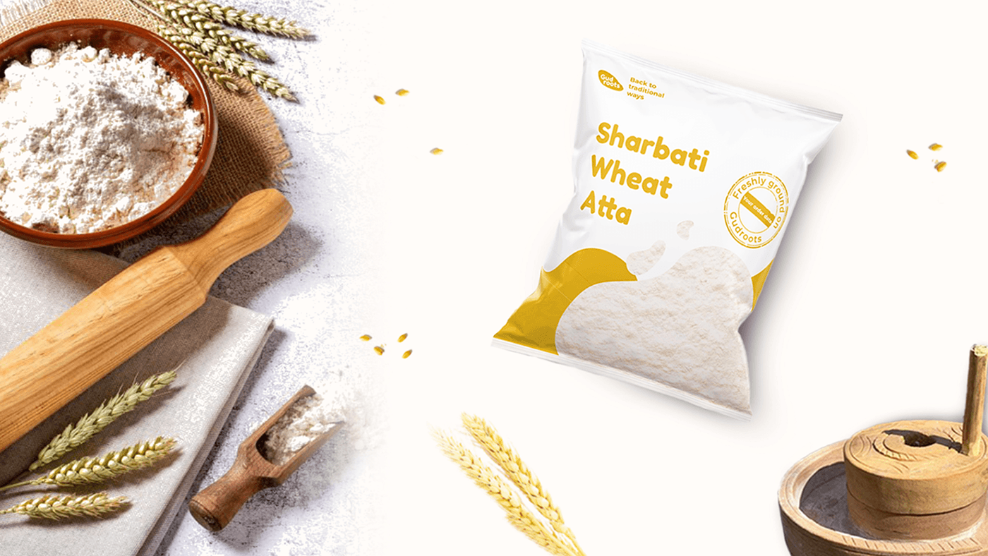 Gudroots Sharbati Wheat Atta pouch beside a bowl of flour, wheat and a rolling pin