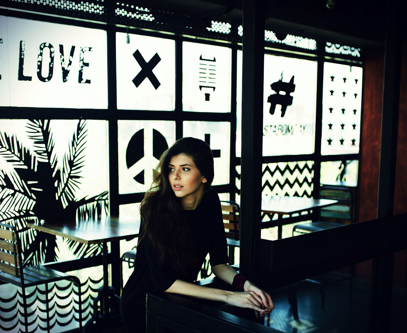 Mood reference of a young woman sitting at a cafe window with graphic patterns