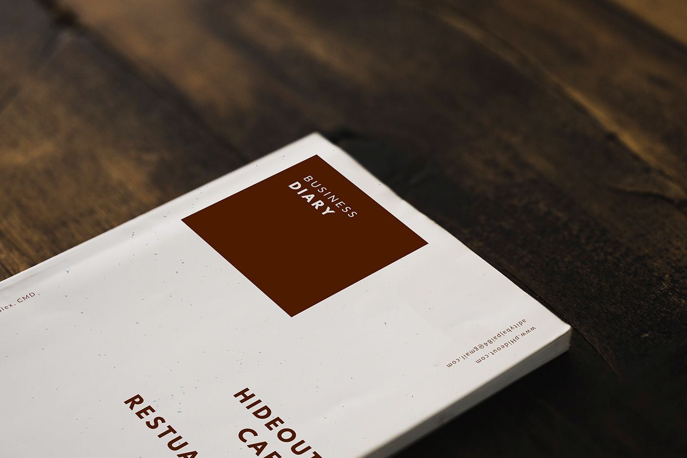 Hide Out Cafe business diary with a brown label on a dark wood table