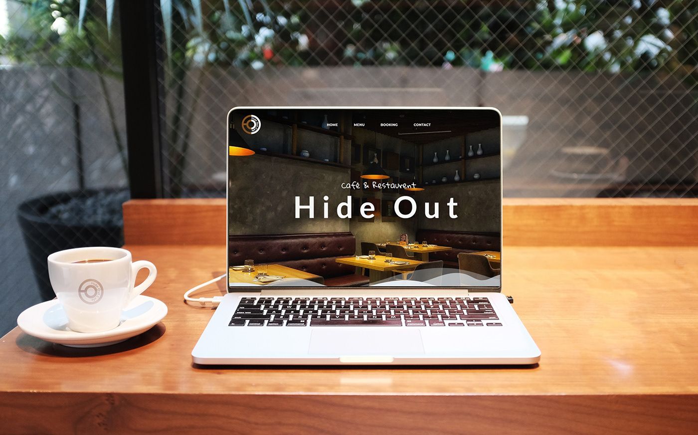 Hide Out Cafe website on a laptop beside a coffee cup with the logo