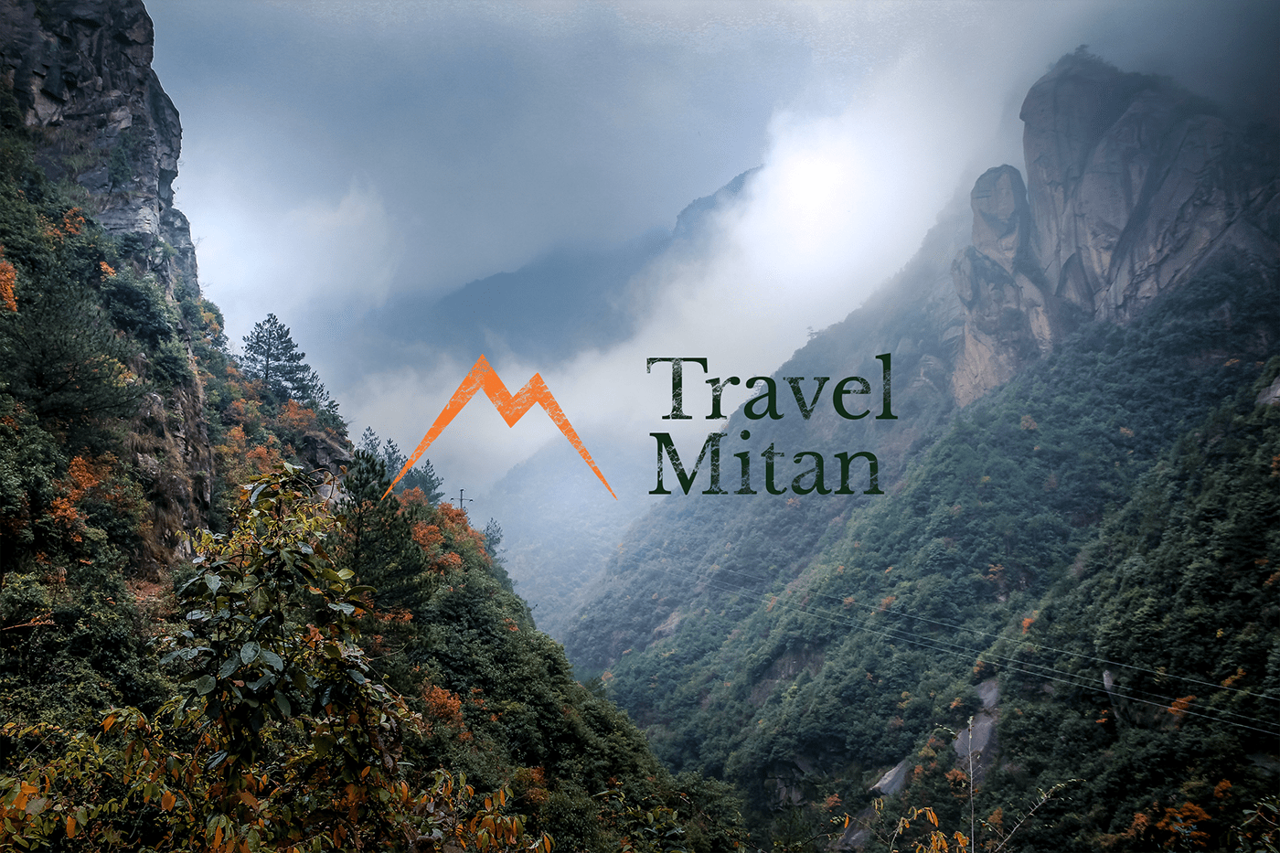 Travel Mitan logo over a misty forested mountain gorge