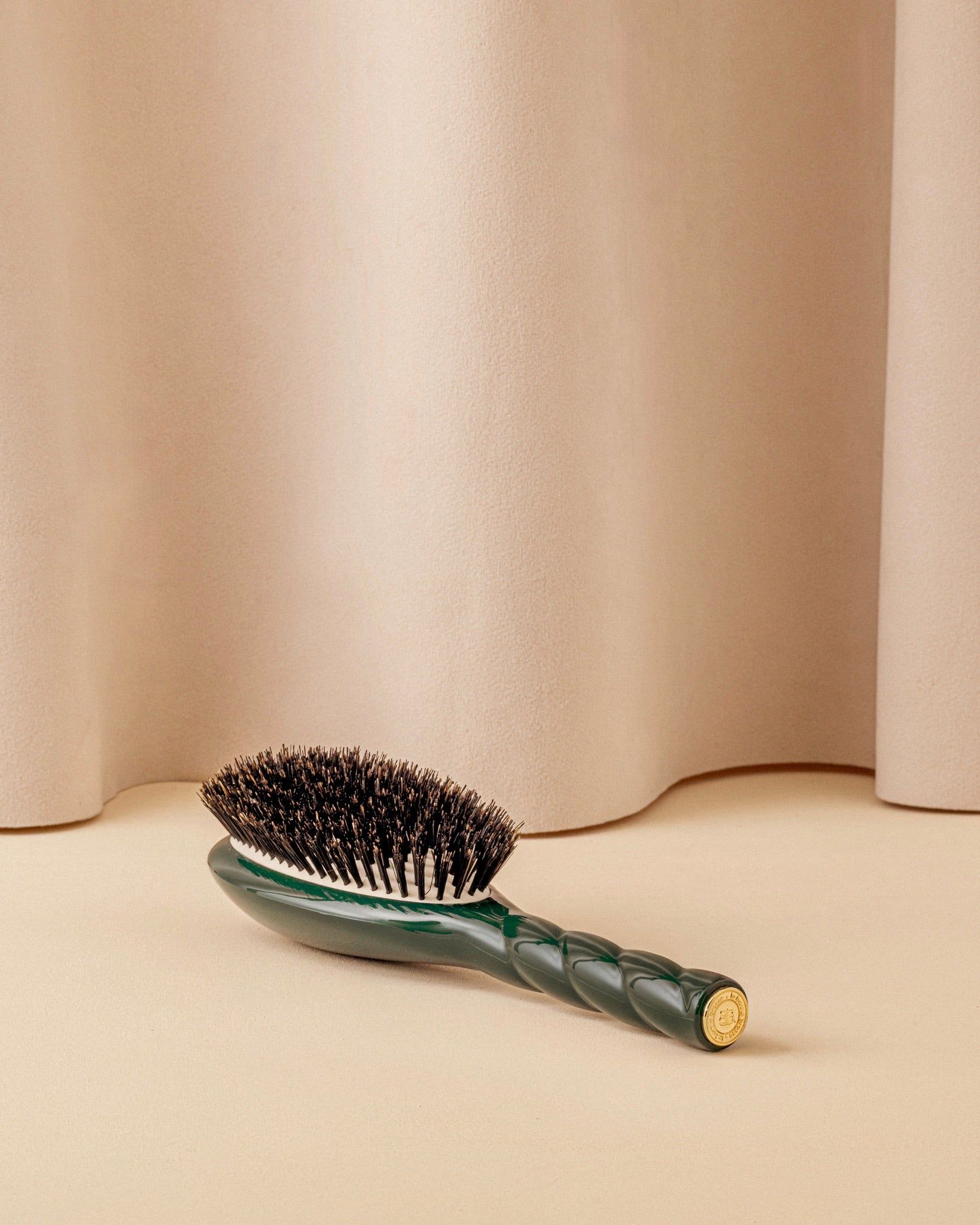 Emerald green La Bonne Brosse N.01 lying on its side against a beige backdrop