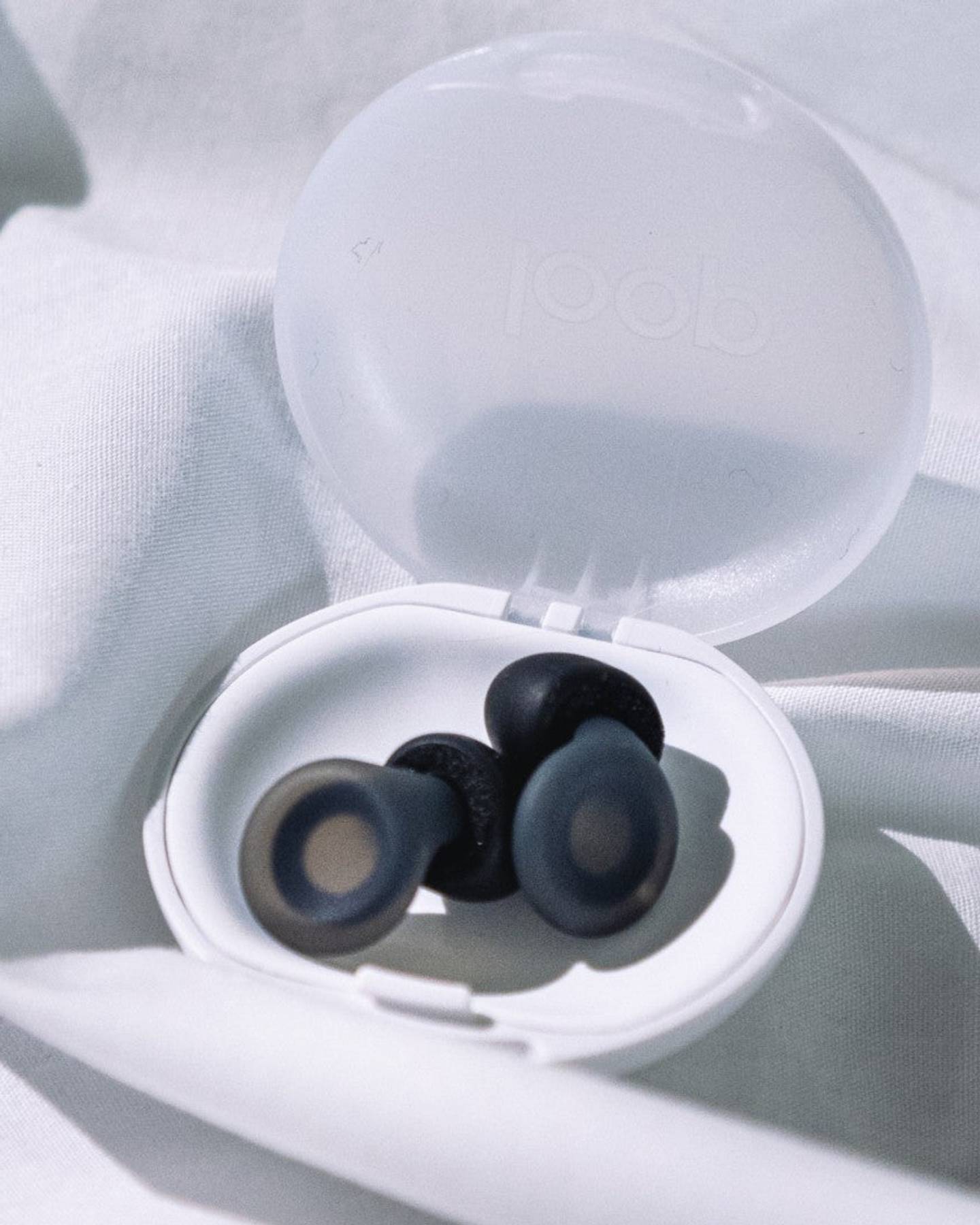Black Loop Dream earplugs resting in their open bedside carry case