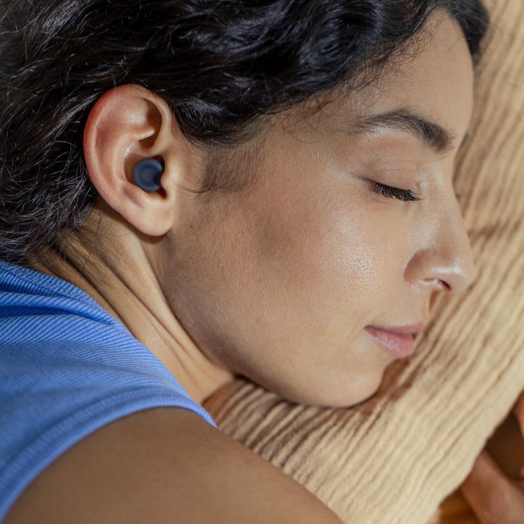 Woman sleeping on her side wearing a black Loop Dream earplug