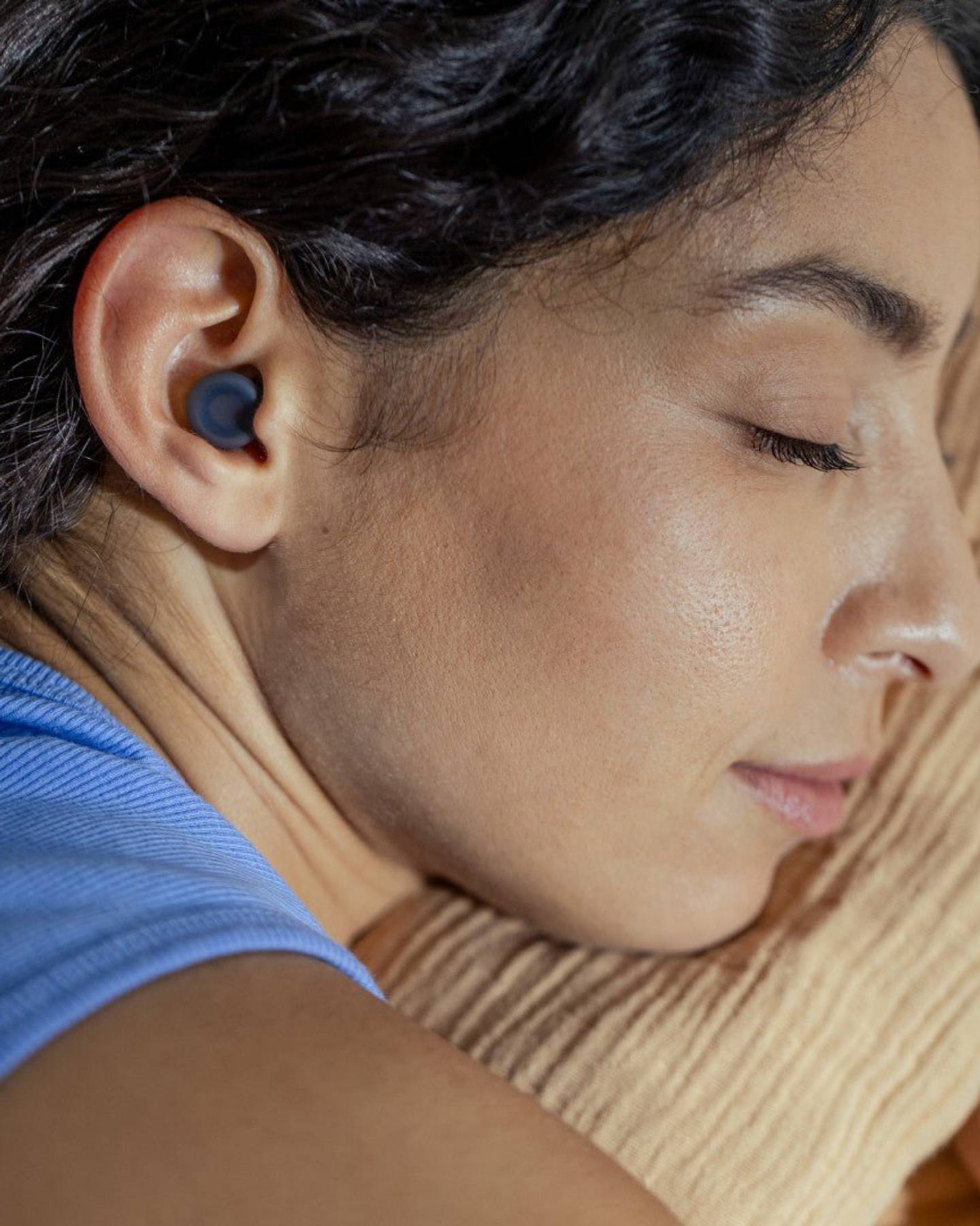 Woman sleeping on her side wearing a black Loop Dream earplug