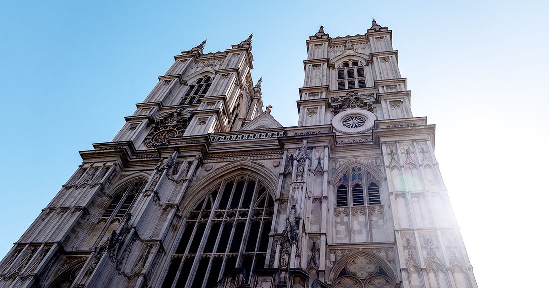 Exterior view of Westminster Abbey in London, England, with its iconic Gothic towers rising against a clear blue sky.