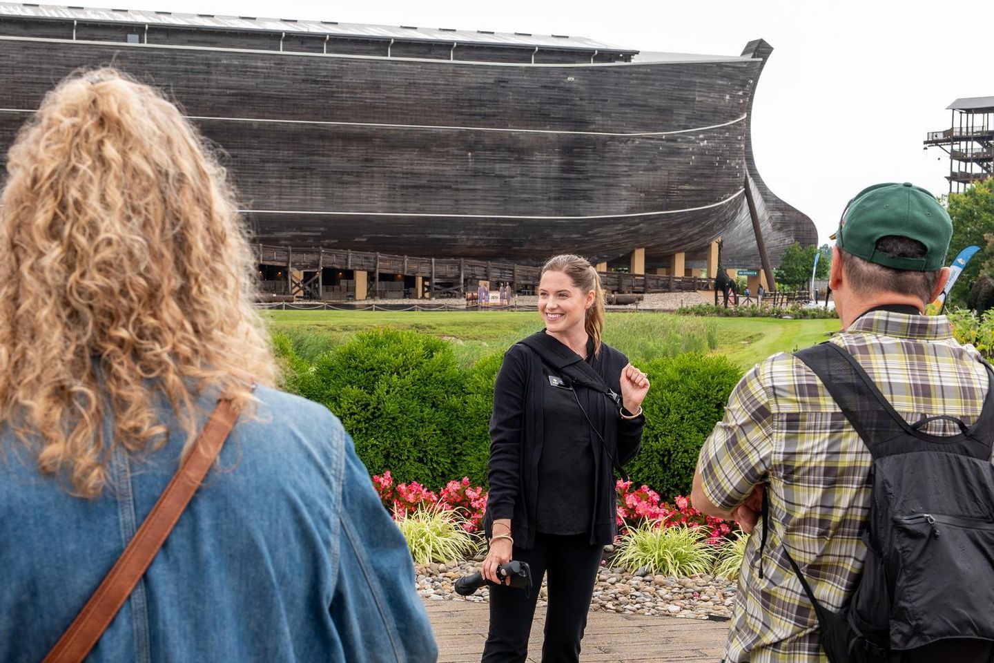 An Inspire guide welcomes guests outside the Ark Encounter, introducing the life-size Noah's Ark before a guided tour.