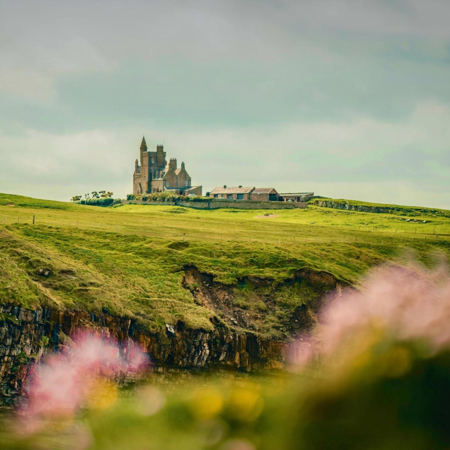 Historic stone abbey overlooking the green countryside and rugged coastline of Ireland.