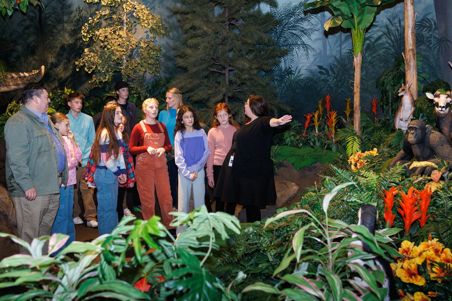 An Inspire guide explains God's creation to guests in the Creation Museum's Garden of Eden exhibit, surrounded by lifelike animals and lush vegetation.