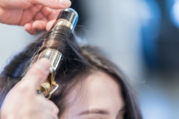 Closeup of unrecognizable hairdresser using curling iron - stock photo In this closeup of the top of a female customer