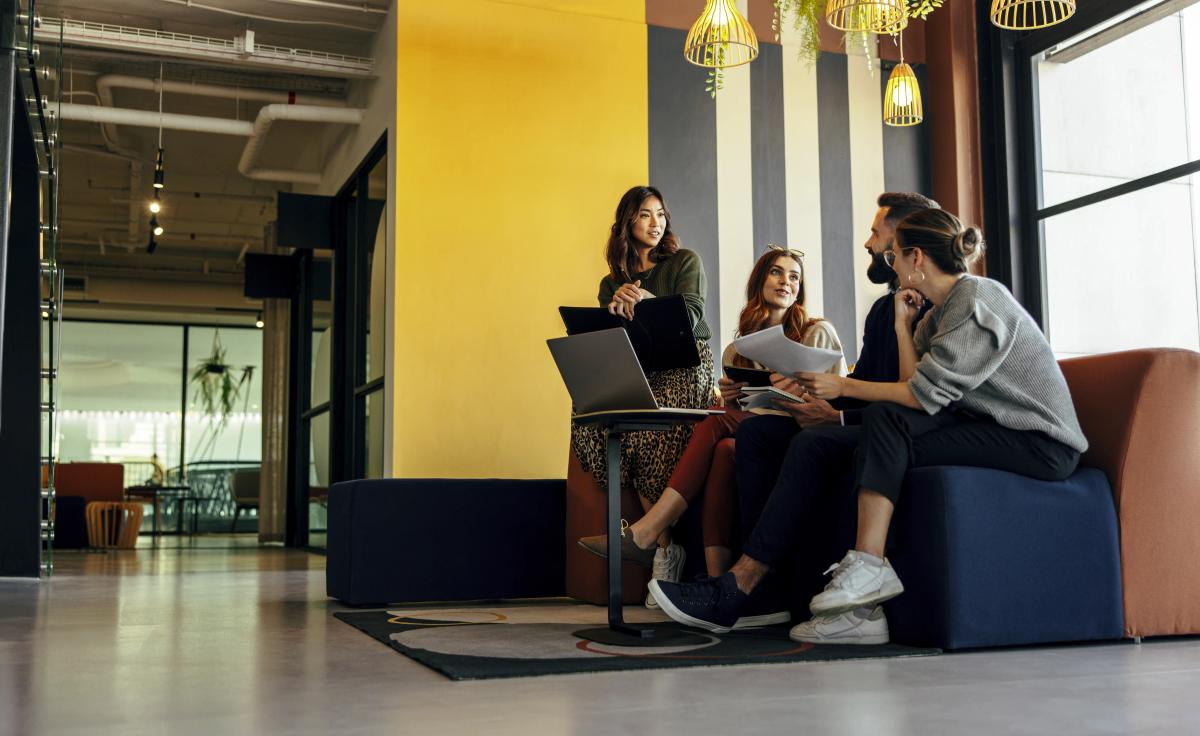 une équipe se réunit dans un petit salon au sein d’un espace de coworking pour une réunion informelle