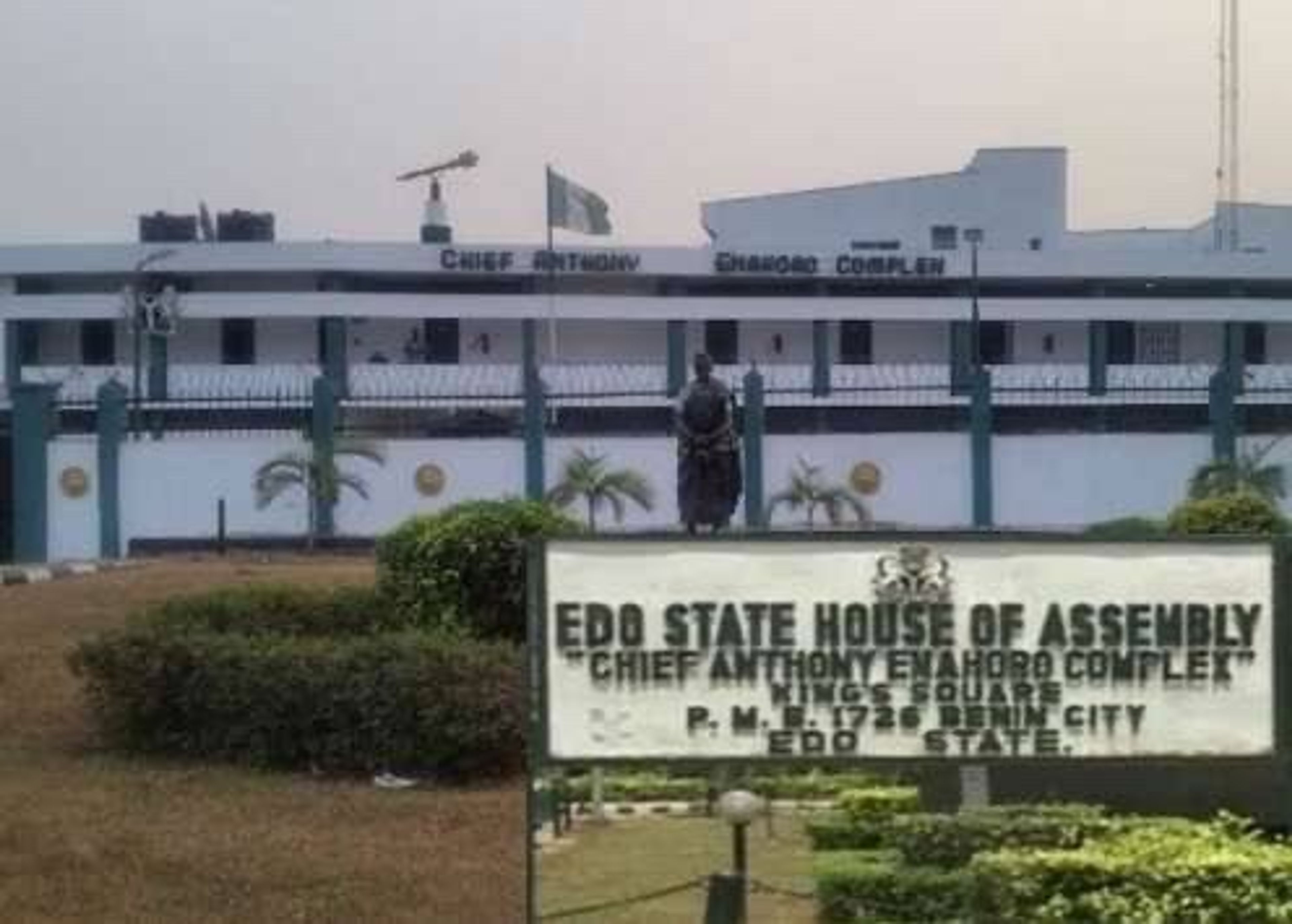 Signboard for the Edo State House of Assembly in front of the white legislative complex and flagpole