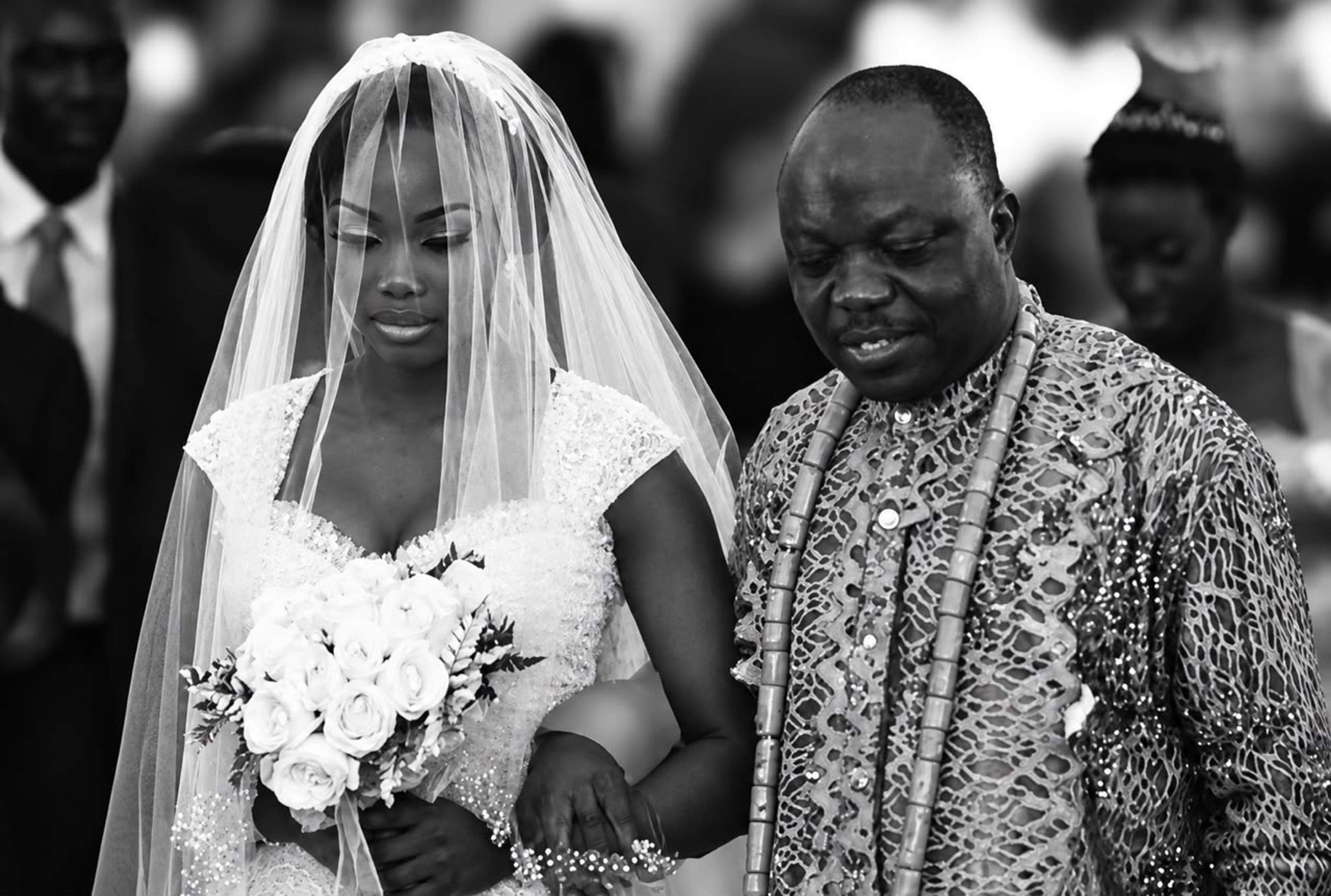 Orode Uduaghan in a white wedding gown, hands in her father's Emmanuel Eweta Uduaghan