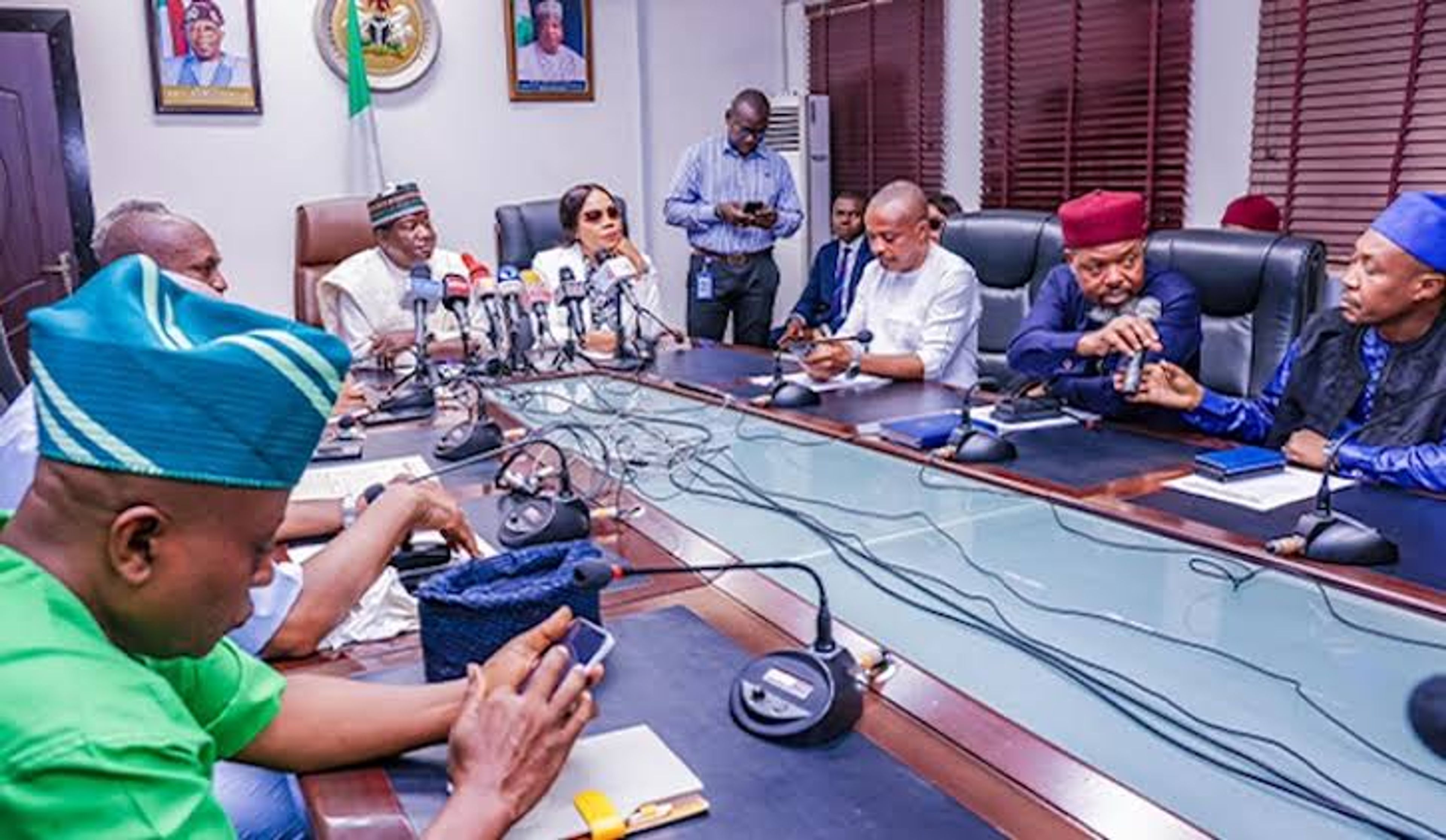 Officials and union leaders seated around a conference table with microphones during a meeting in a government boardroom