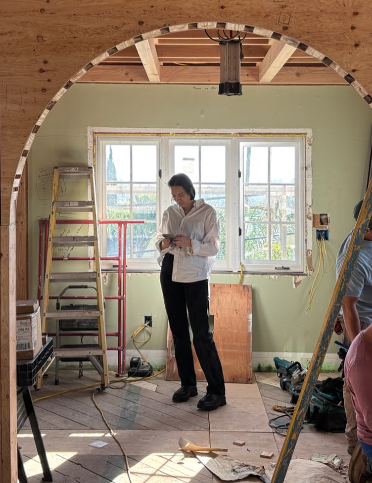 woman looking down at her desk that is filled artwork and art supplies