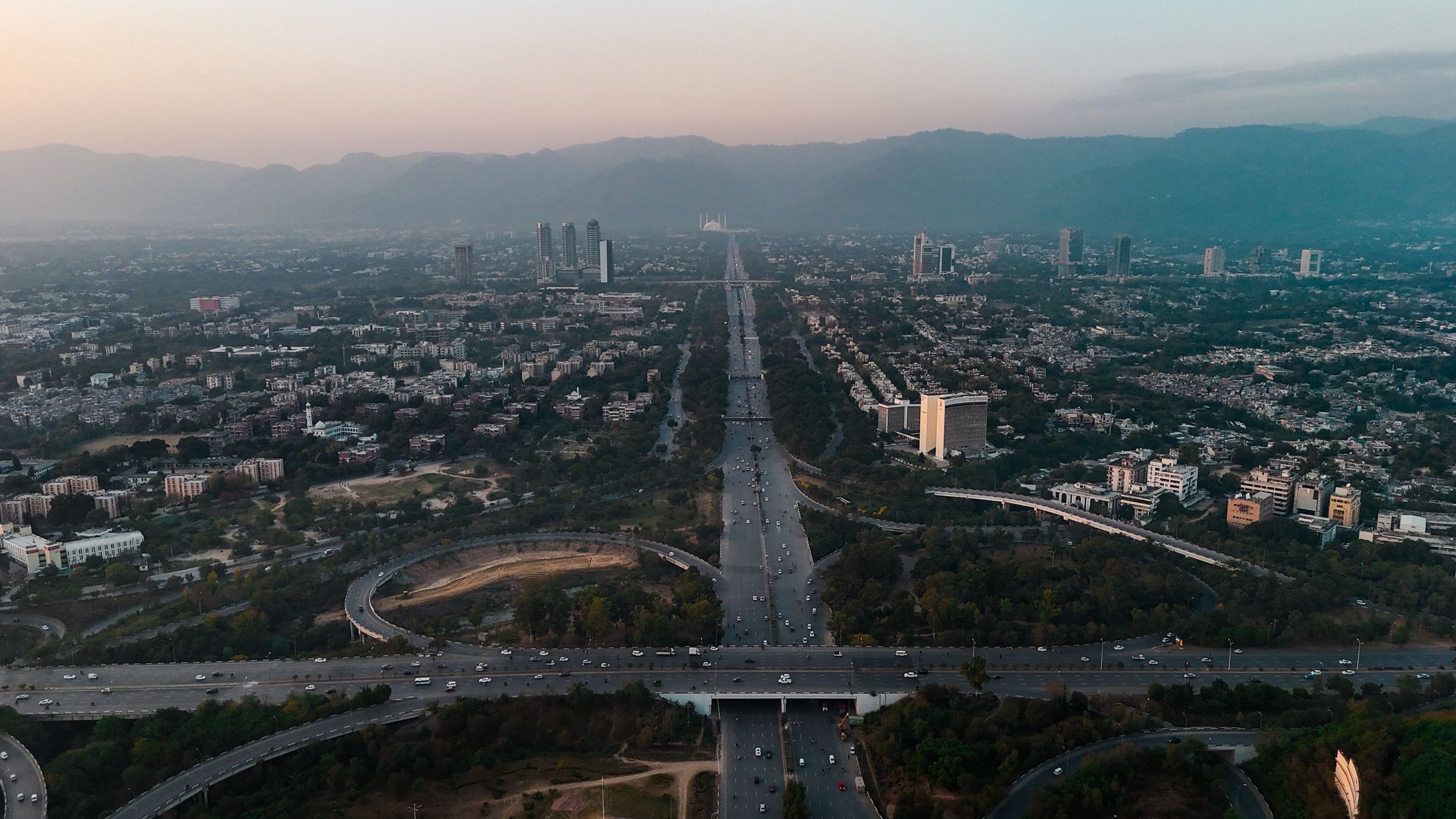 Aerial view of Islamabad with highways, buildings and the Margalla Hills at dusk