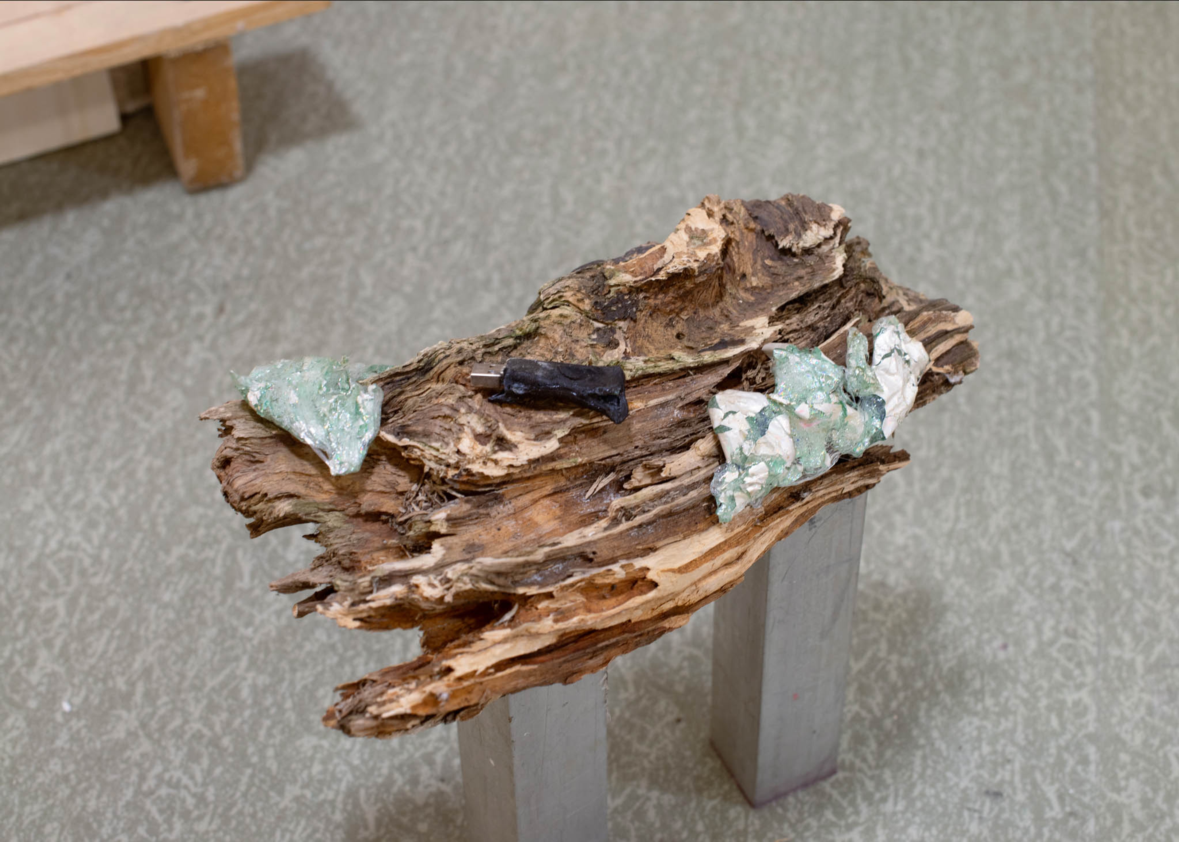 Melted bits of plastic lay on an old piece of wood.