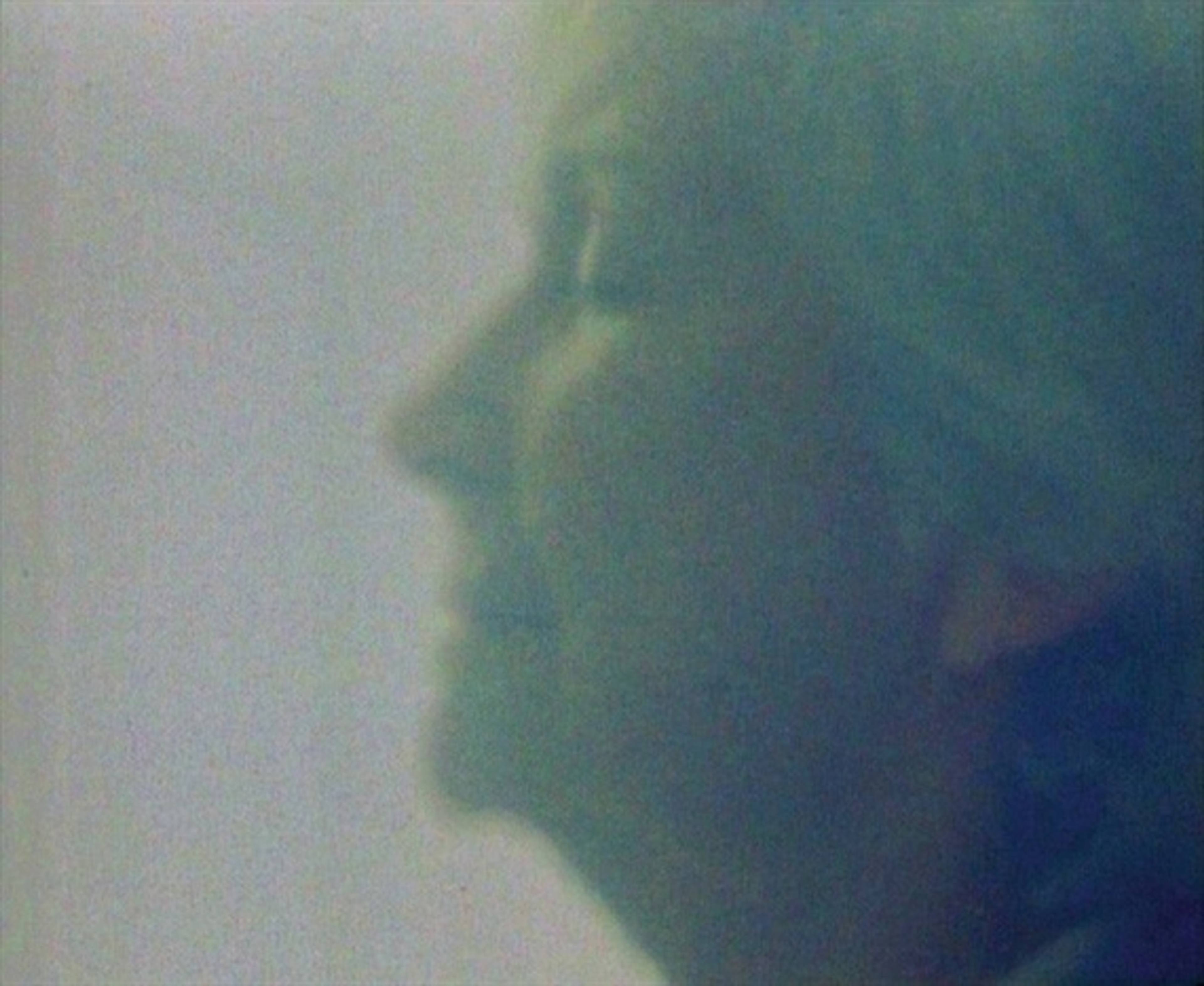 The profile of a woman faces towards light with eyes closed