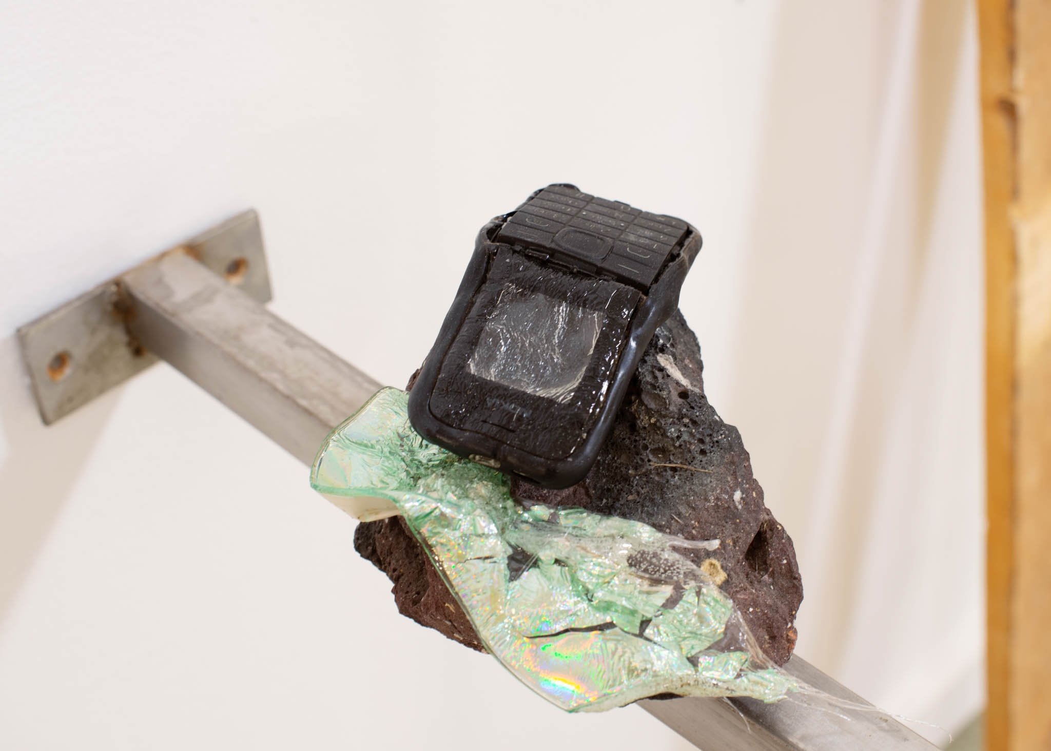 A melted phone and bits of plastic lay over a stone