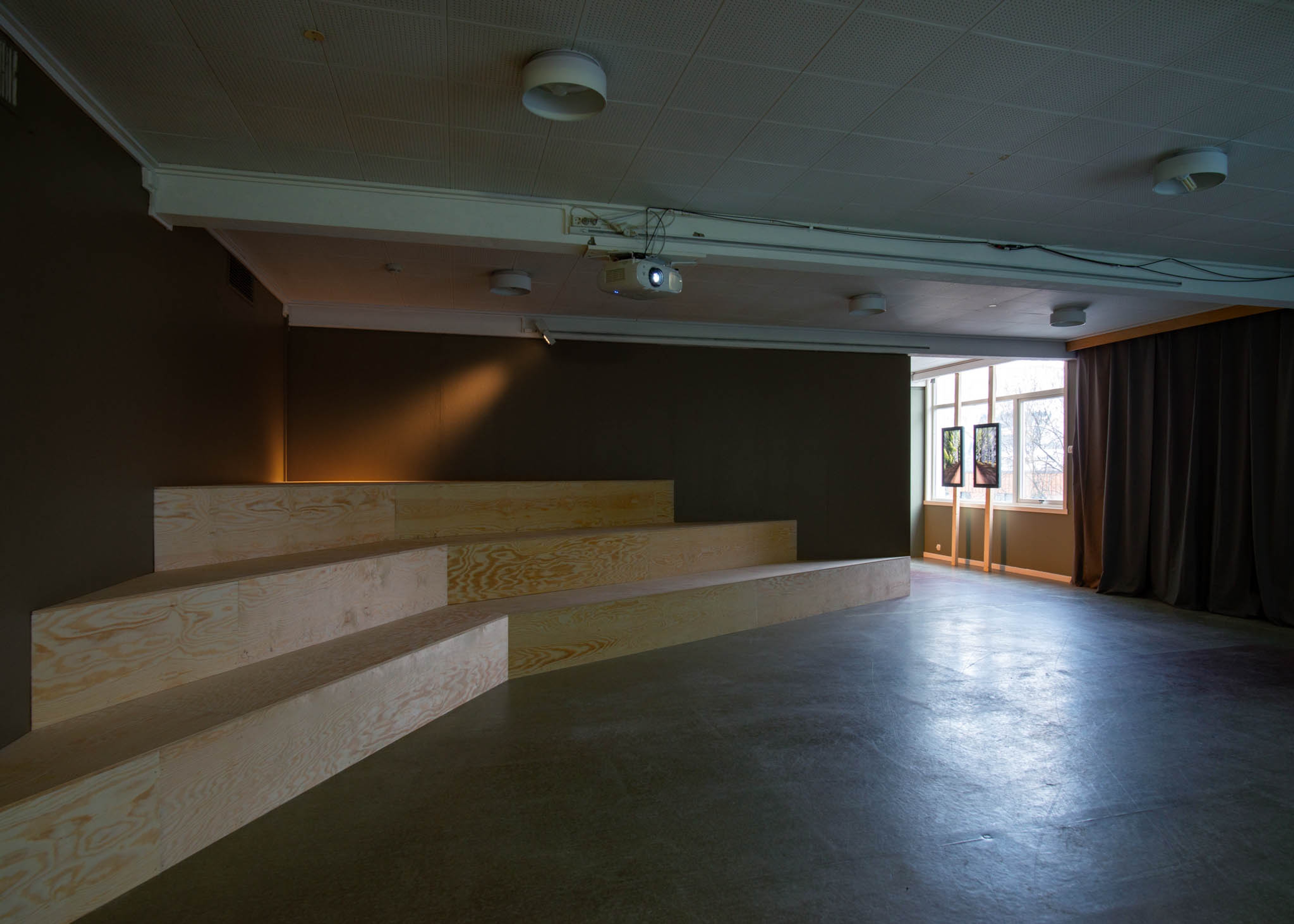 A wooden amphither with three tiers is lit with a spotlight.