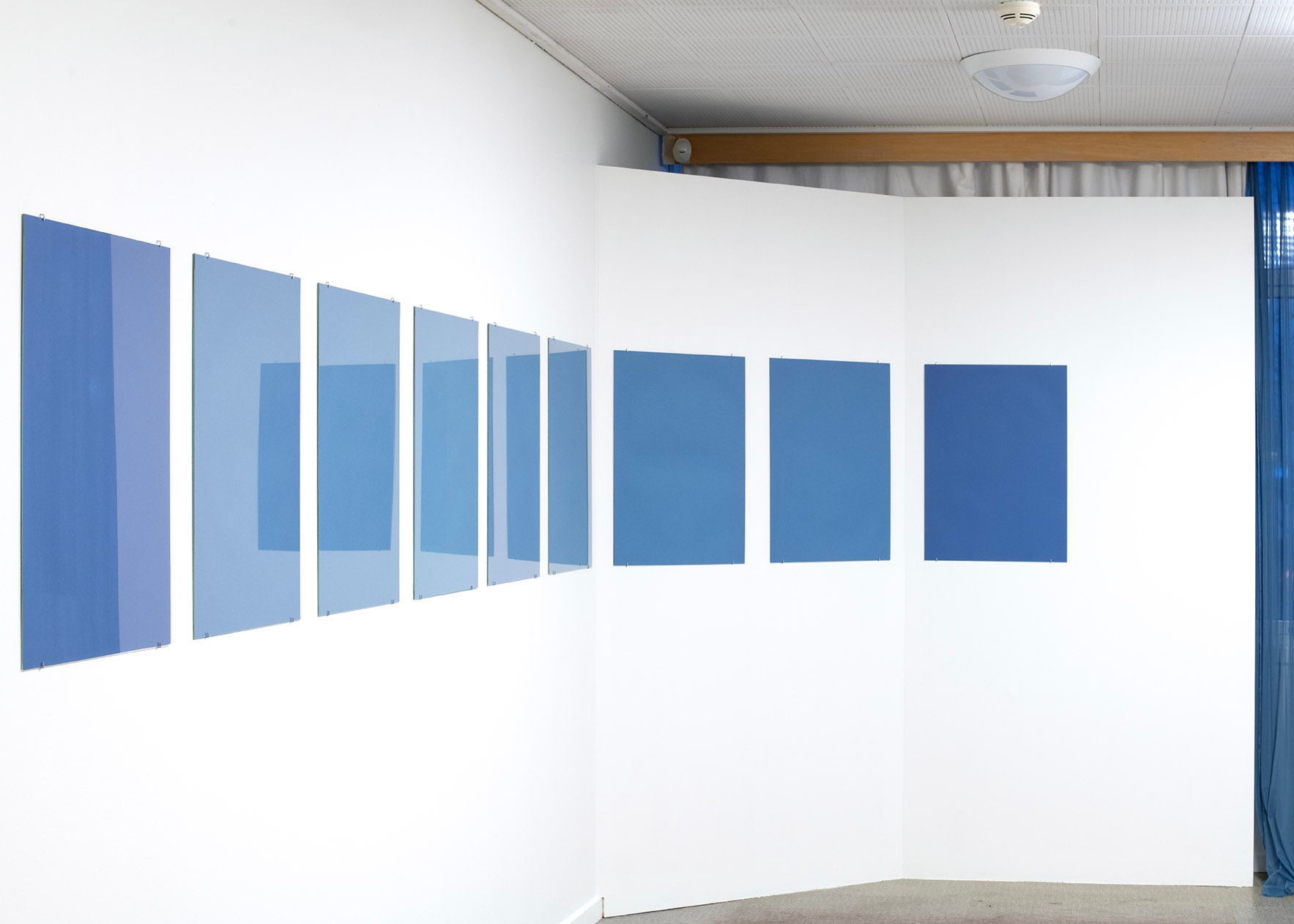 Blue papers hang in a straight line on a white wall