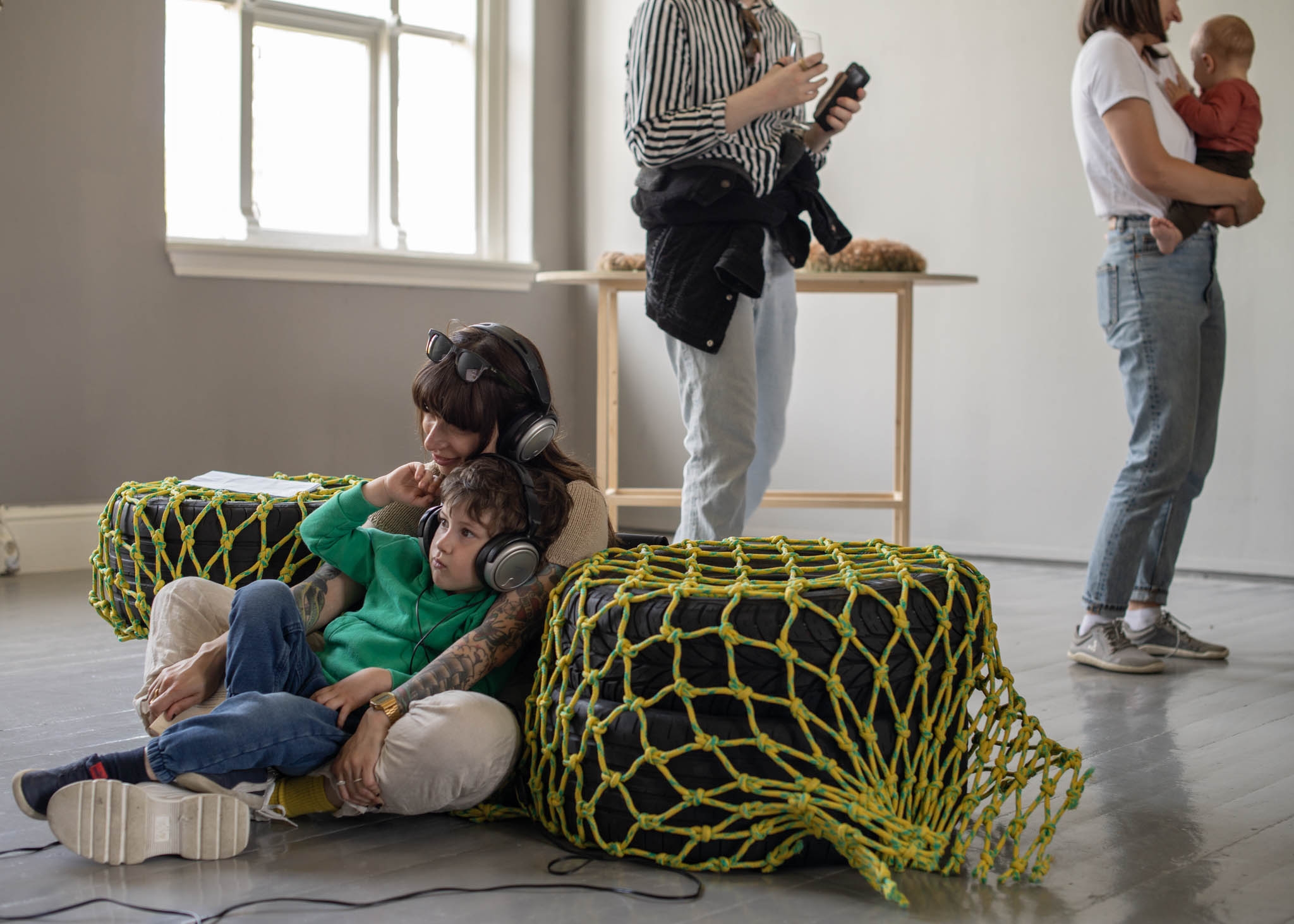 A women and child sit together on the floor, listening to headphones