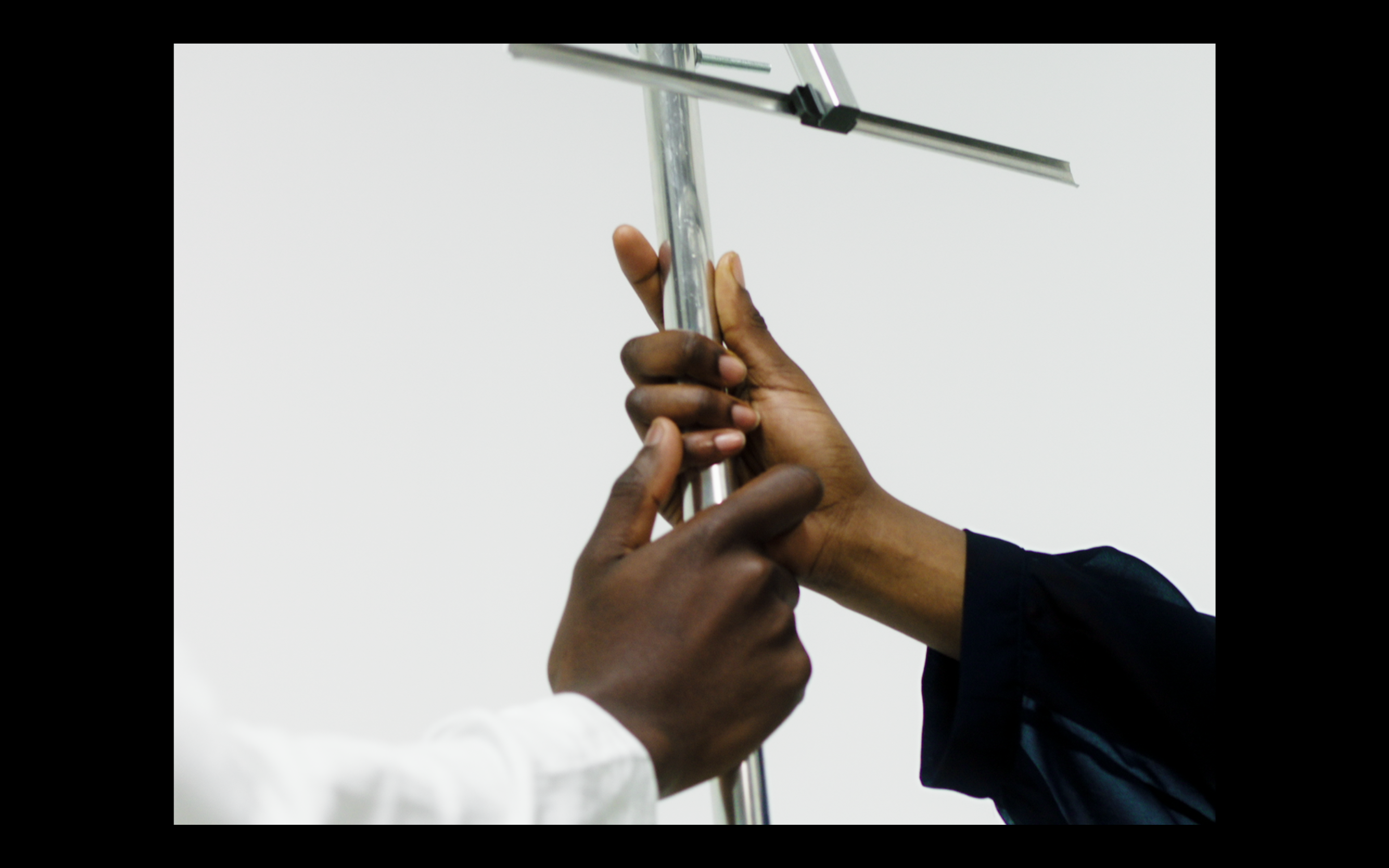 Two black hands grasp the base of a silver antenna