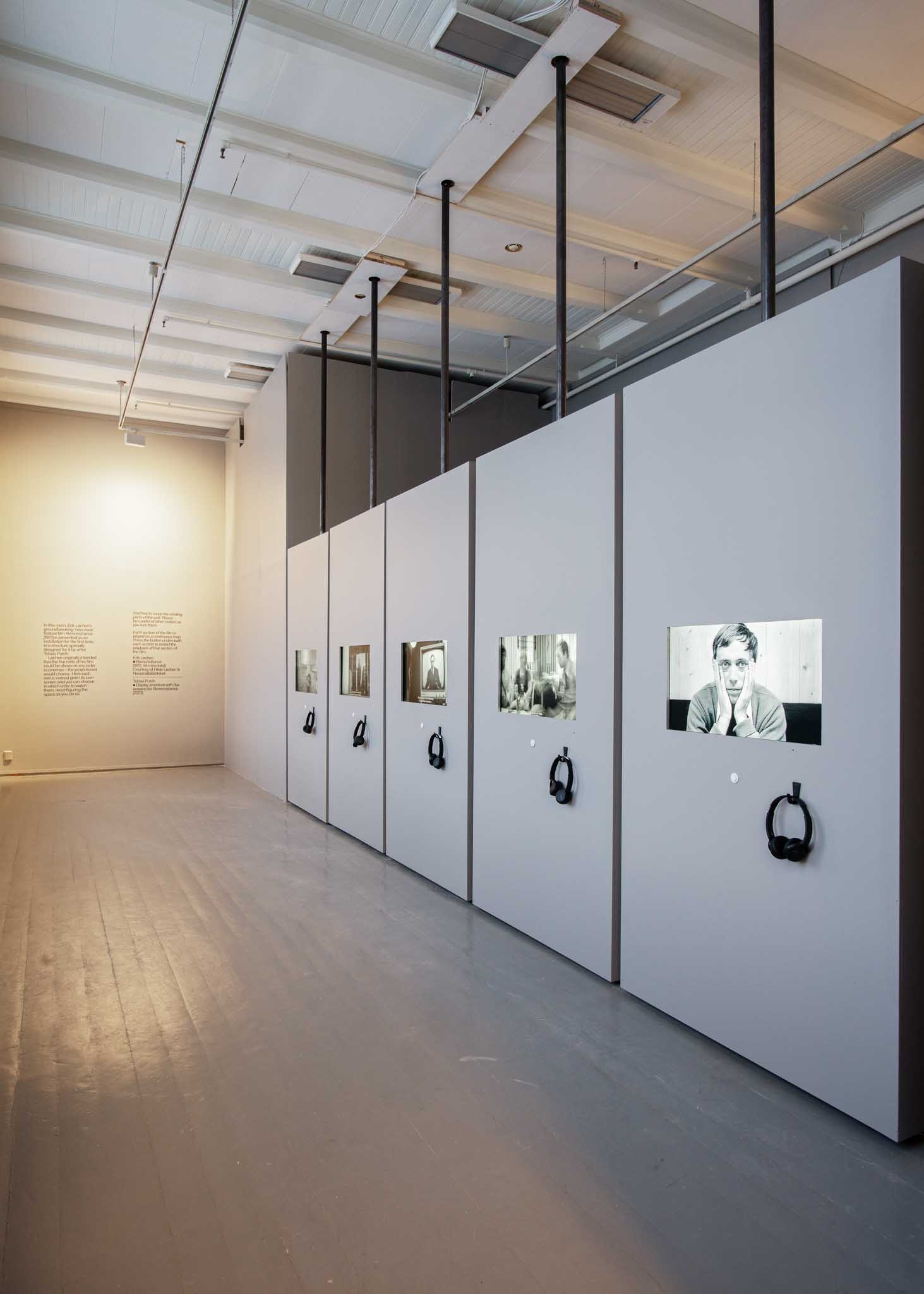 Vertikale paneler er justert i en vegg, med TV-skjermer i hver som viser et svart-hvitt-bilde.