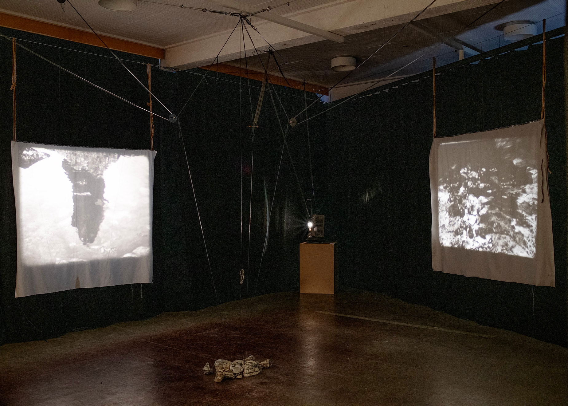 An analogue projector in between two fabric projection screens in a dark room