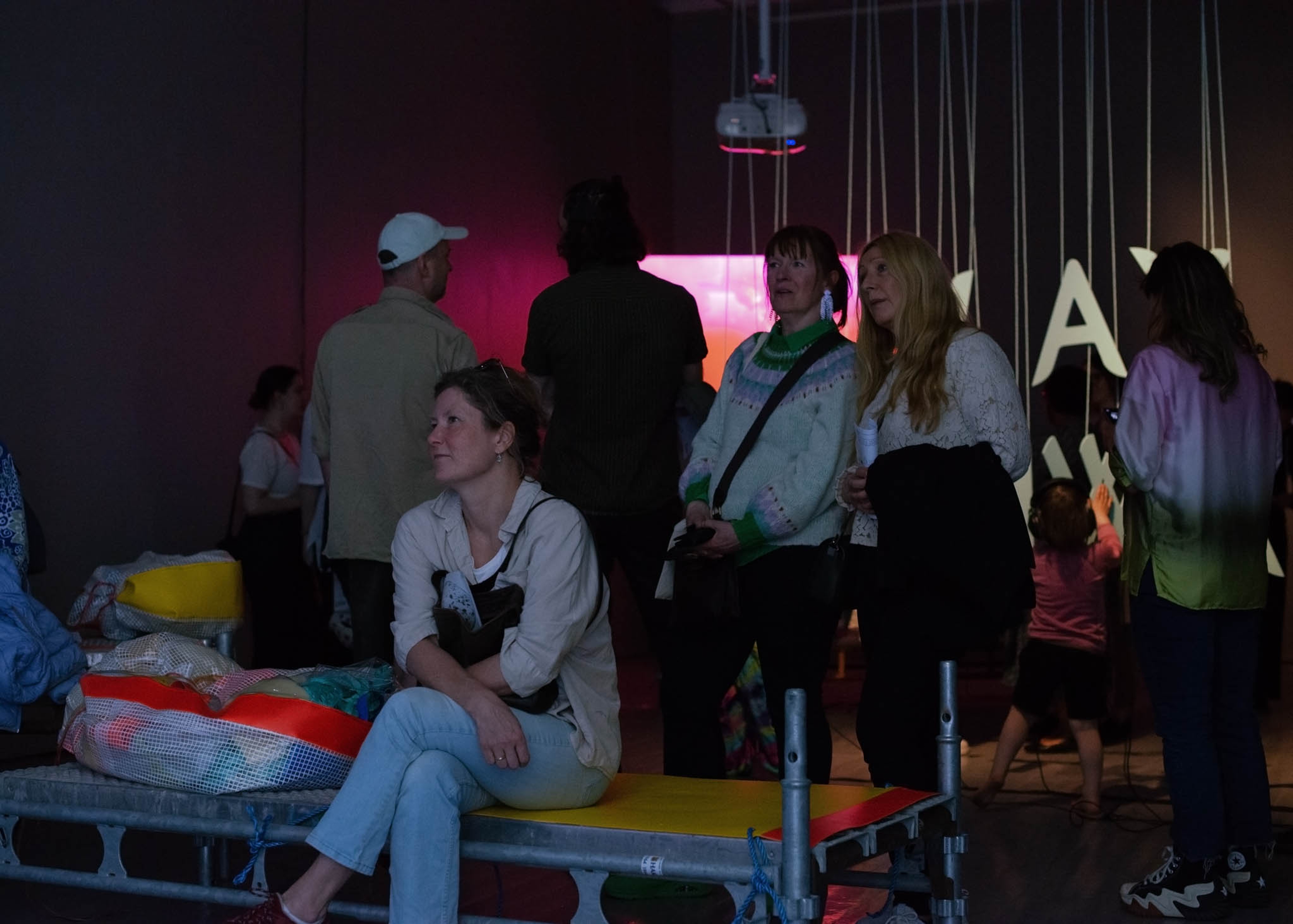 Many people looking around in a dark gallery.