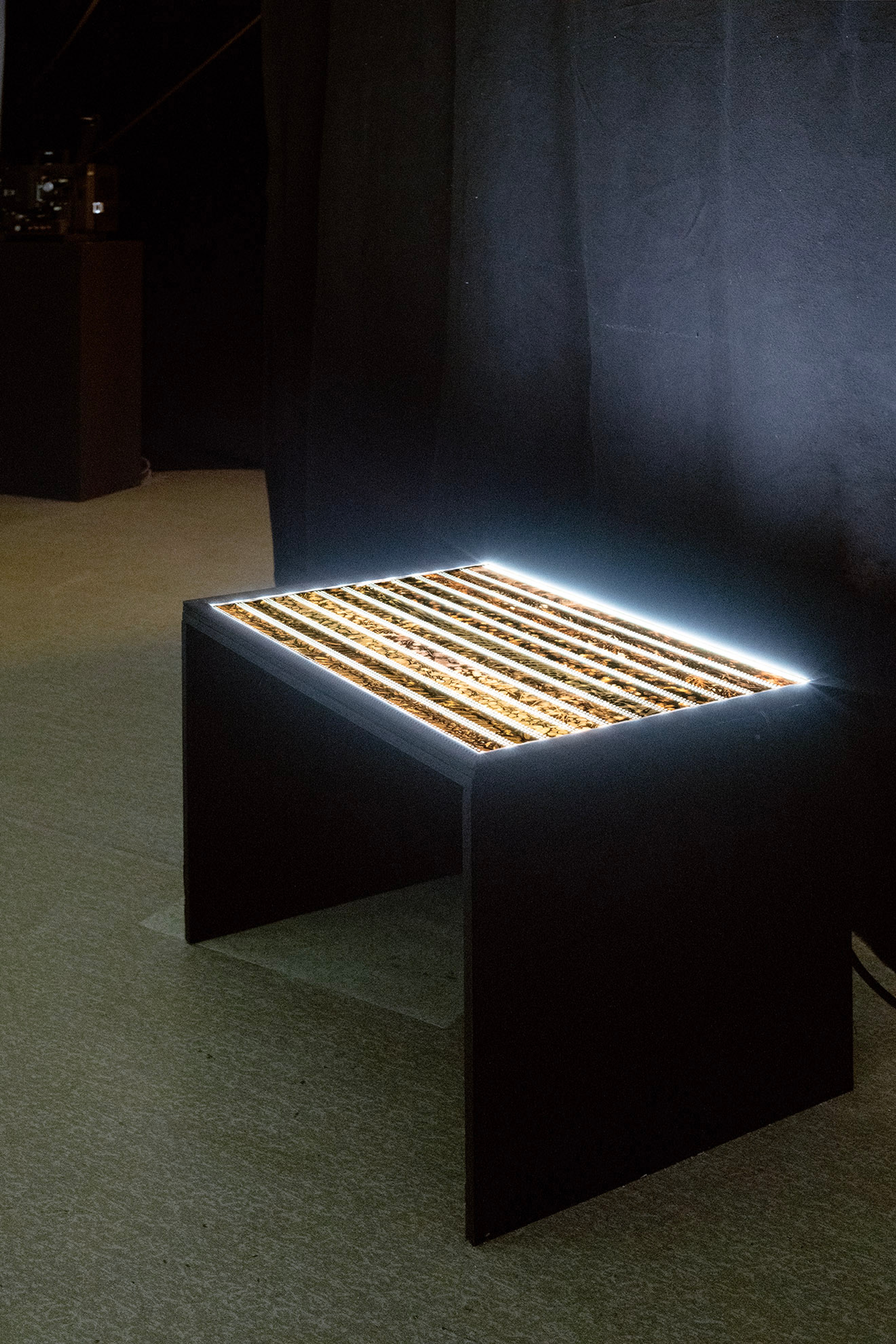 A light table with film strips on it glows in a dark gallery