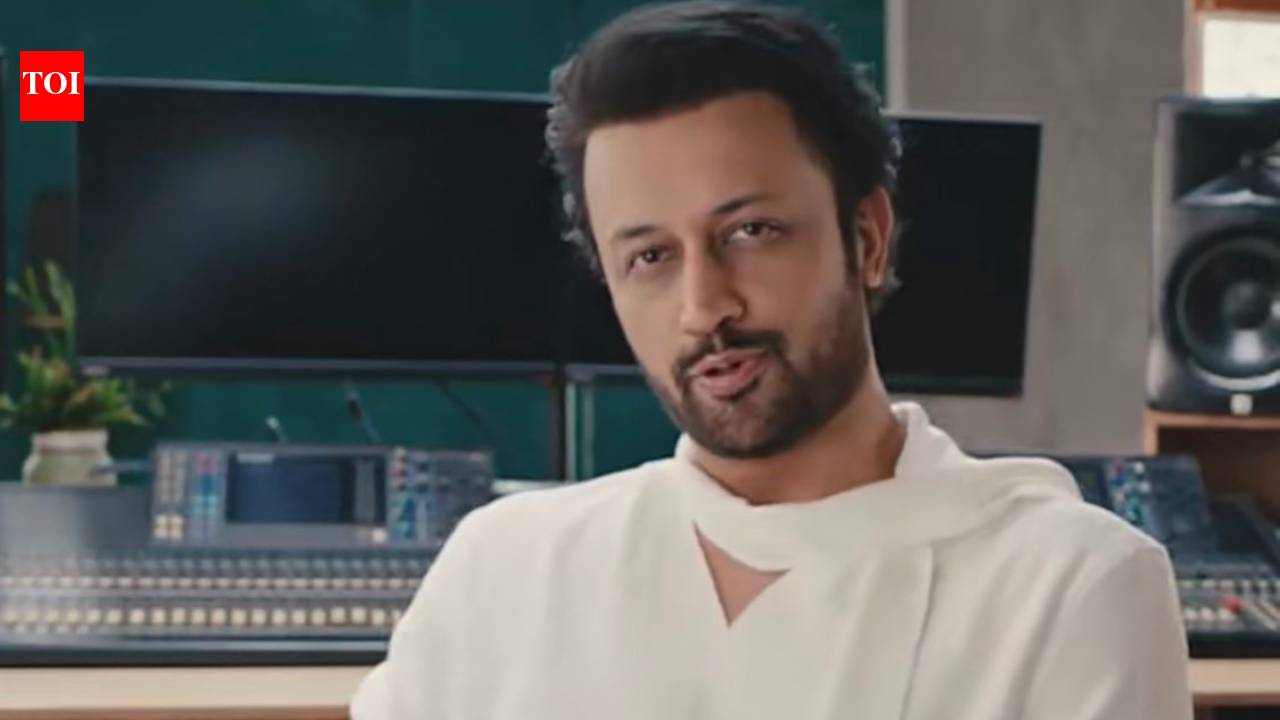 Atif Aslam performing on stage with a crowd of fans in the background