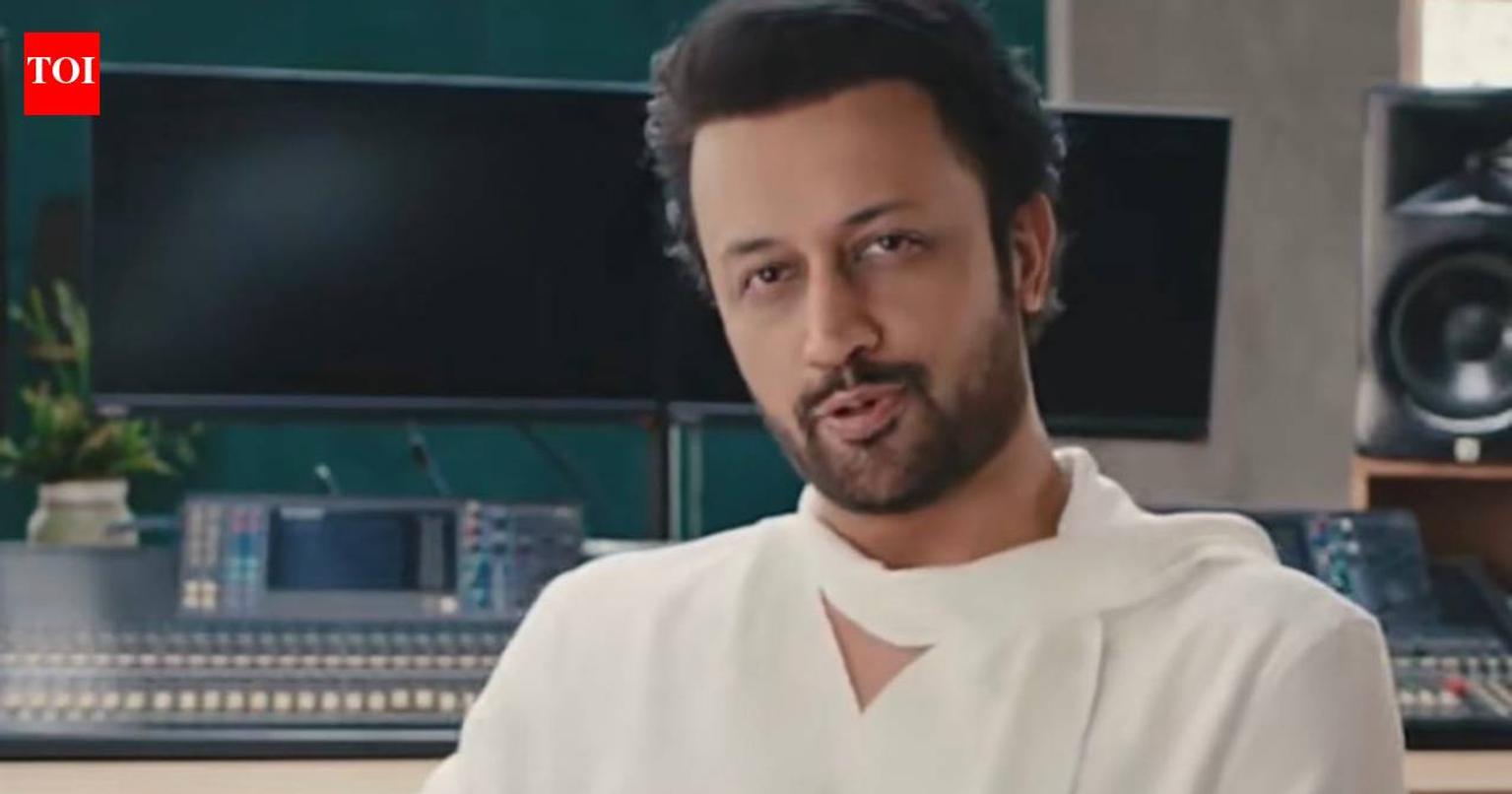 Atif Aslam performing on stage with a crowd of fans in the background