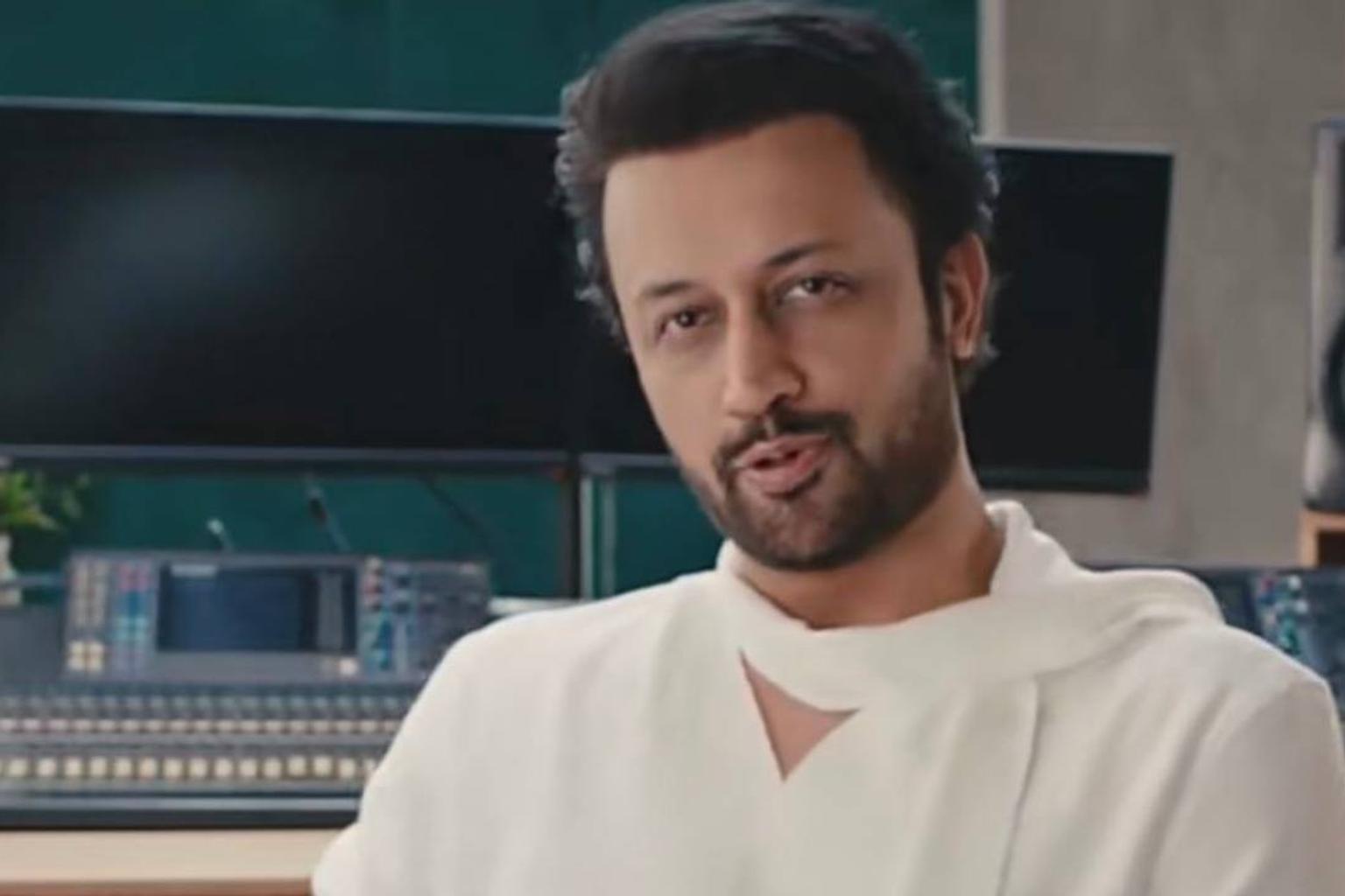 Atif Aslam performing on stage with a crowd of fans in the background