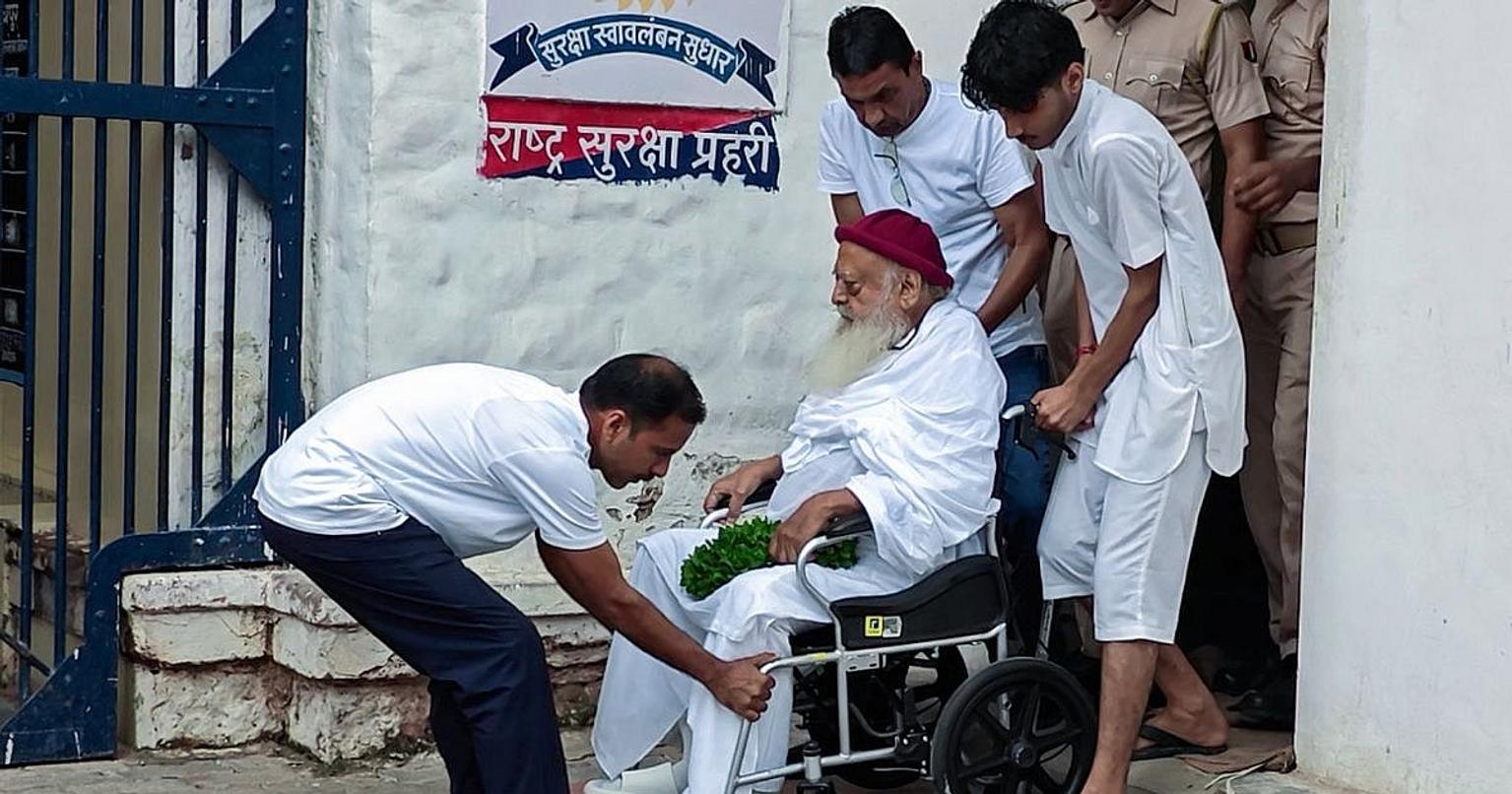 Asaram being led away by police in a crowded courtroom scene
