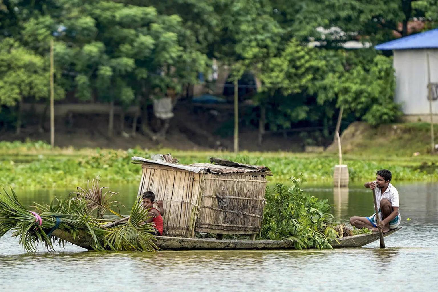 People crossing a flood-affected area on a boat in Morigaon district