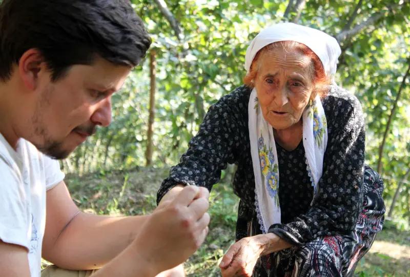En mann og en eldre dame som plukker hasselnøtter