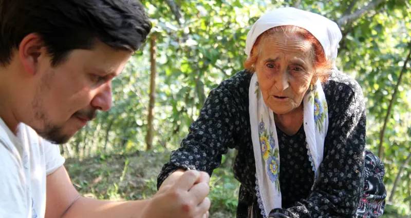 En mann og en eldre dame som plukker hasselnøtter