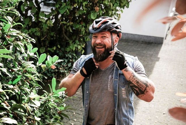 Blid mann tar på seg sykkelhjelm