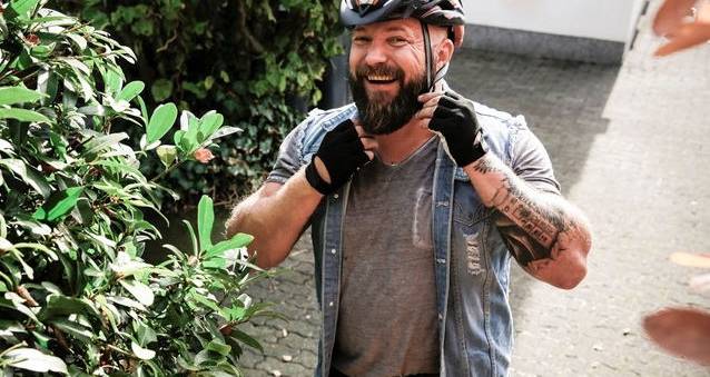 Blid mann tar på seg sykkelhjelm