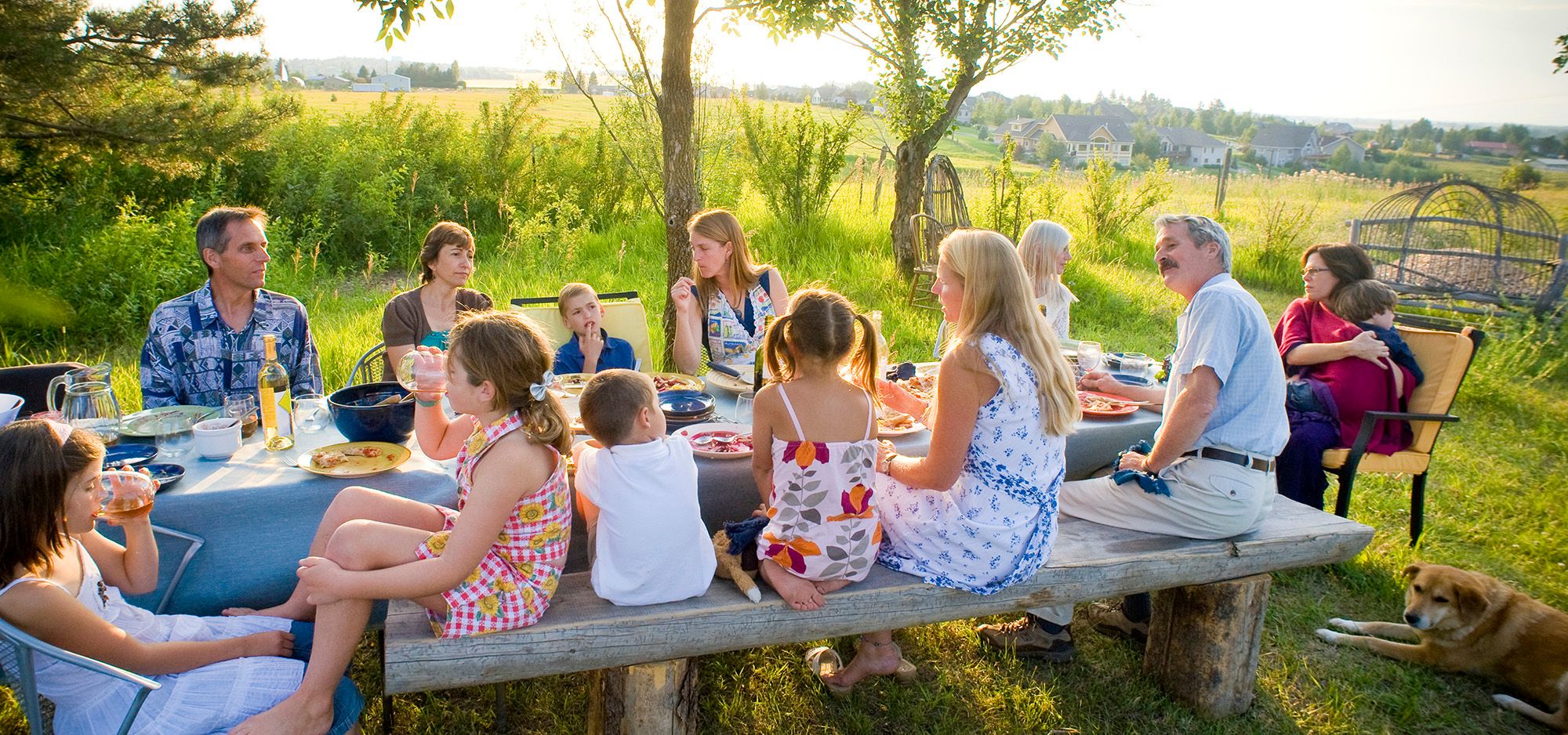 Storfamilie er samlet rundt et måltid i hagen