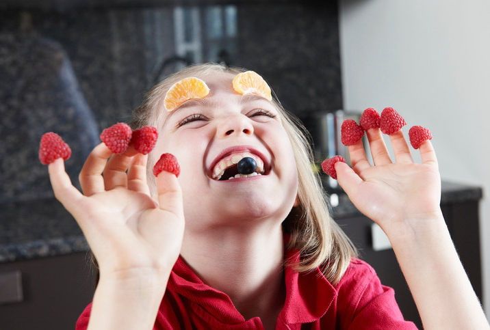 Glad jente har pyntet seg med frukt og bær på fingre og i ansiktet