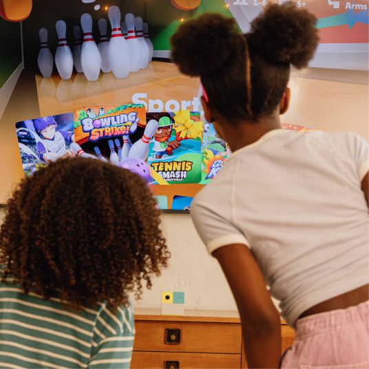 2 girls looking at game content on the tv.