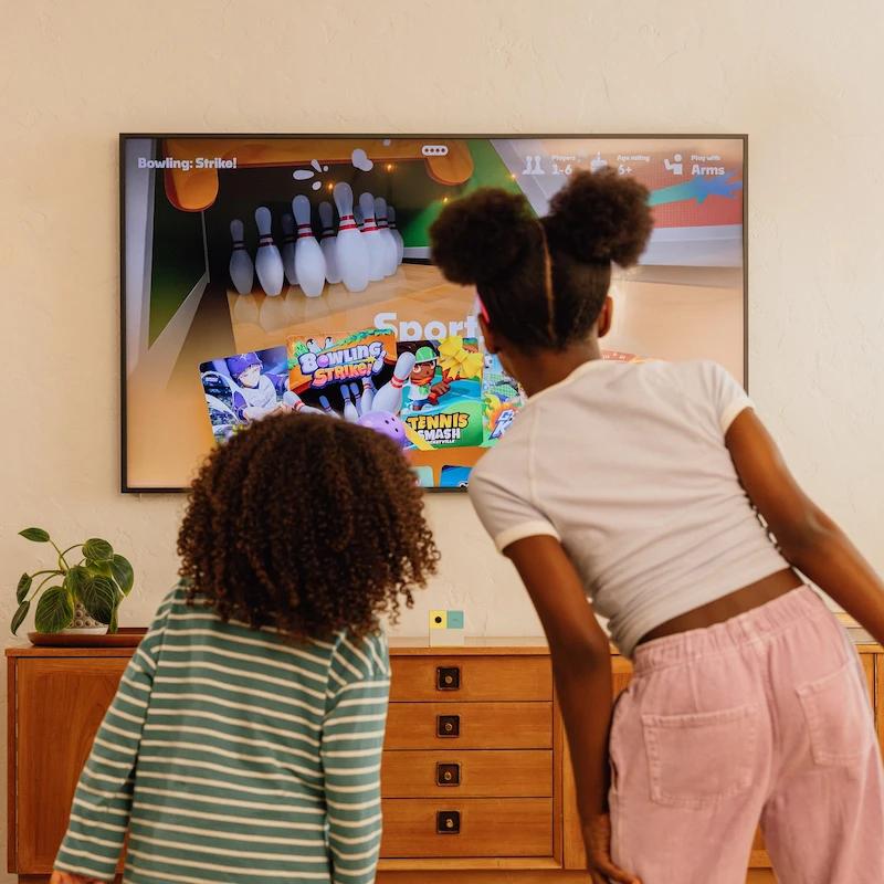 2 girls looking at game tiles on tv
